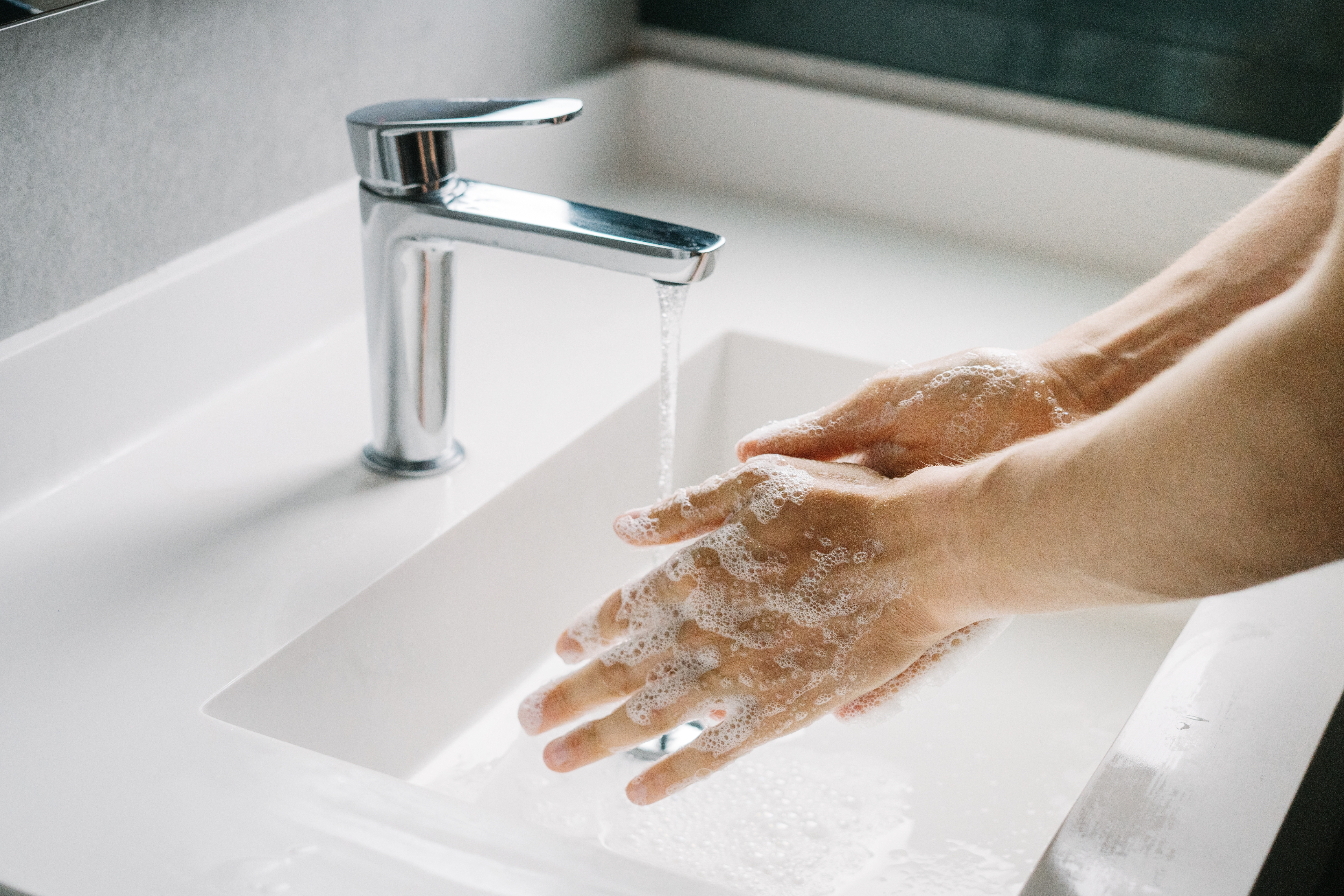 Person washing hands successful a achromatic descend with soap and moving water