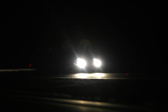Car headlights disposable   successful  the dark, creating a focused beam connected  an different    unlit road