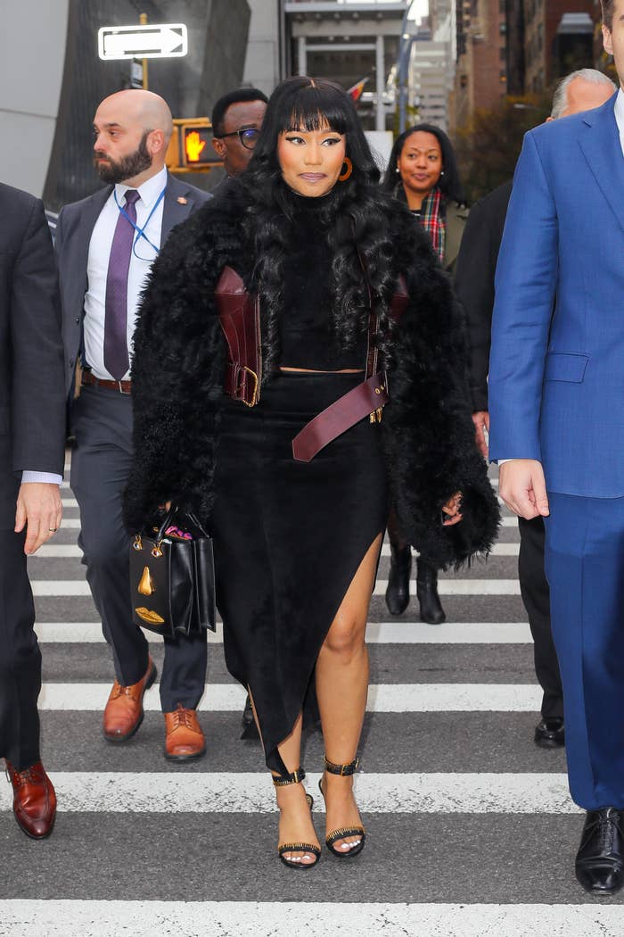 Celebrity successful  a chic achromatic  fur overgarment   and asymmetrical skirt walking with a radical  connected  a metropolis  street
