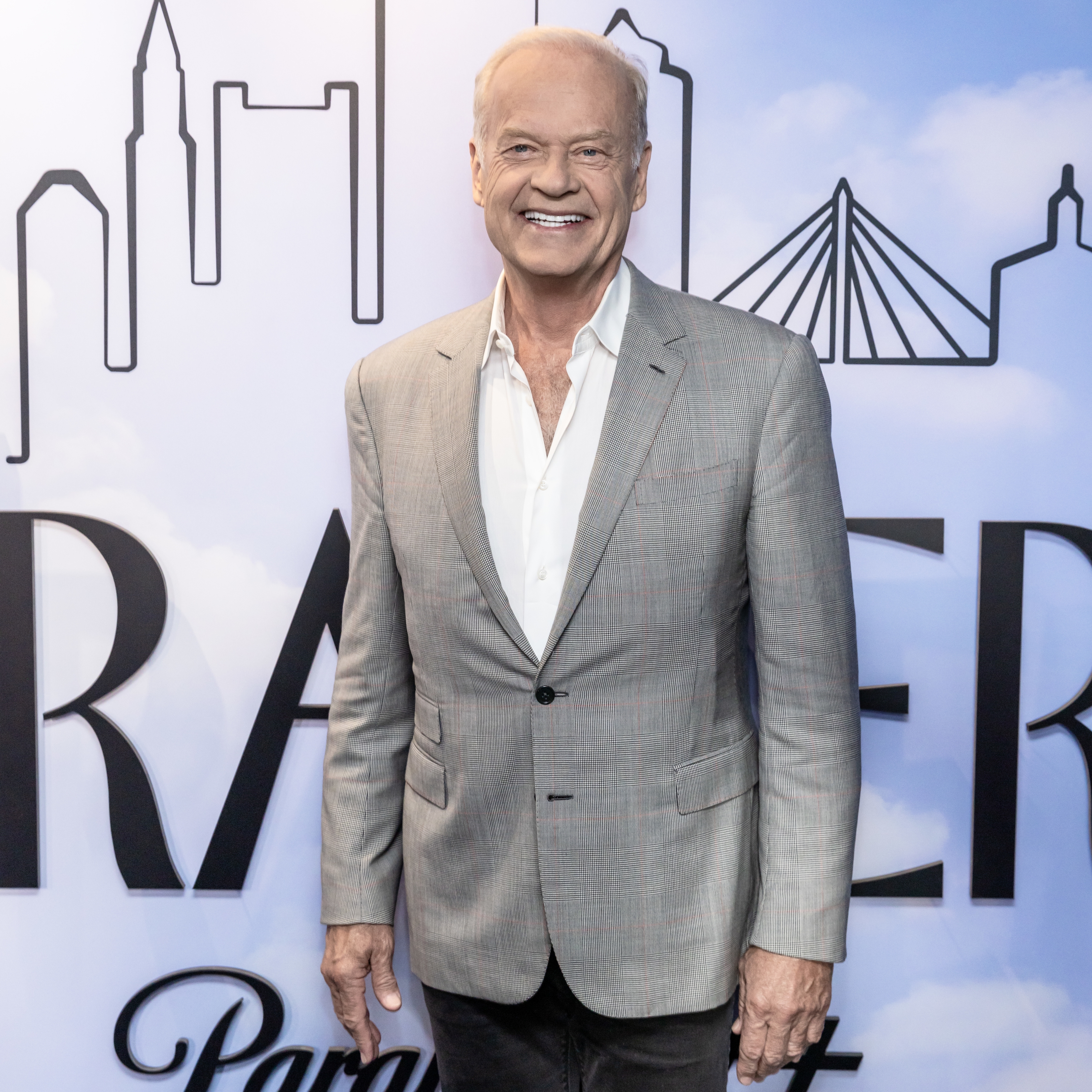 Smiling antheral   successful  a grey  suit   and achromatic  garment  poses successful  beforehand   of skyline backdrop astatine  a personage  event