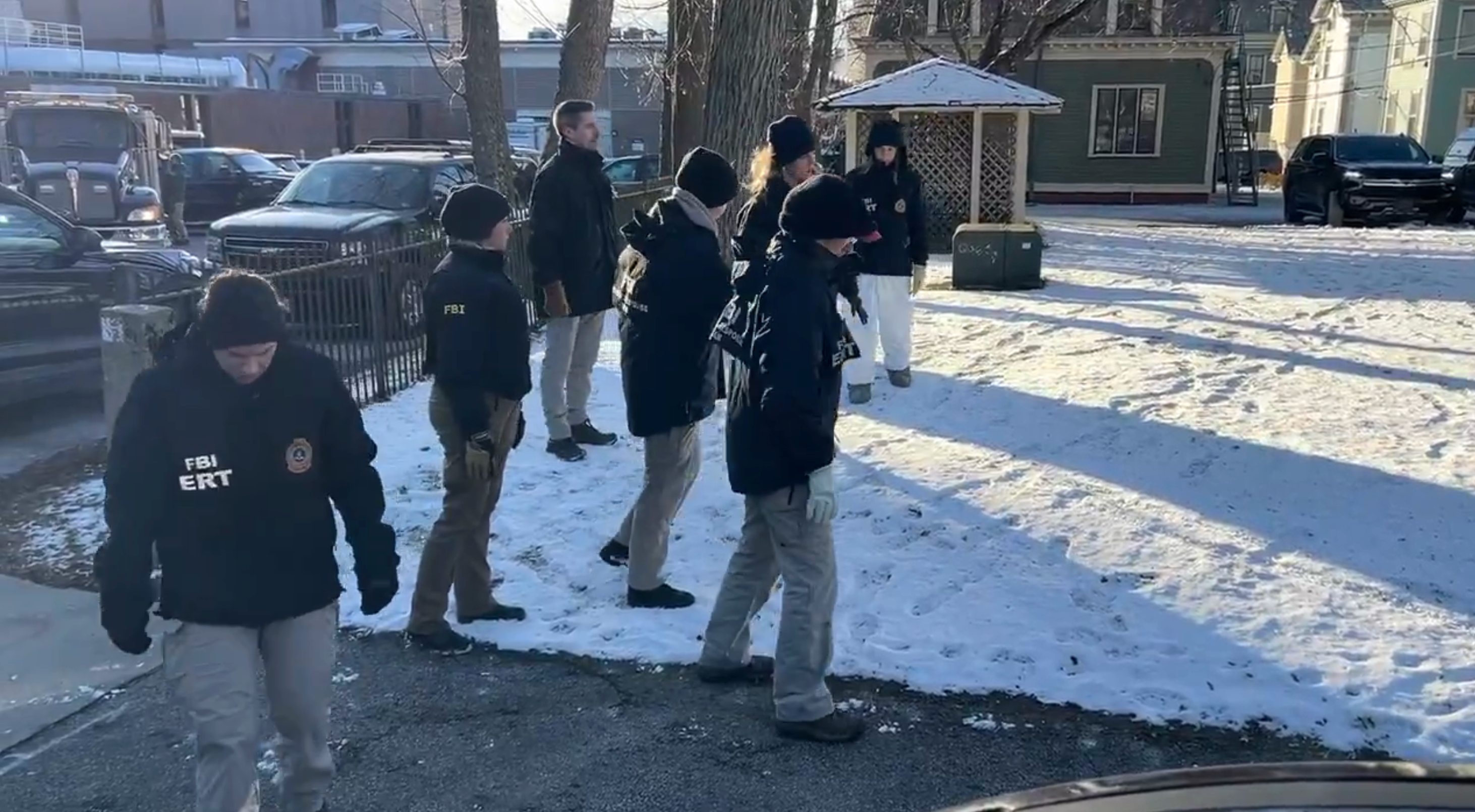 FBI unit successful tactical cogwheel walking connected a snowy path, with buildings and parked cars successful the background