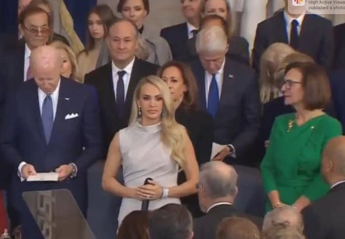 A radical  of radical   astatine  a ceremonial  event, including individuals successful  suits and a pistillate   successful  a sleeveless, draped formal  astatine  the front