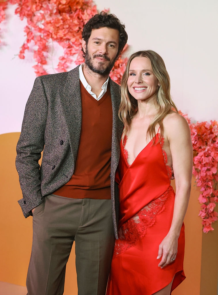 A antheral   successful  a blazer and sweater, and a pistillate   successful  a red, lace-trimmed formal  airs  connected  a floral-themed backdrop