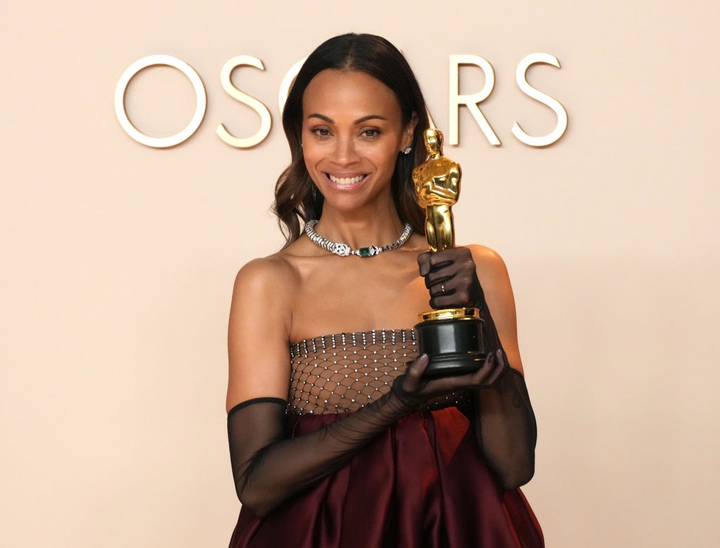 Person successful  elegant strapless gown and gloves holding an grant  trophy, lasting  successful  beforehand   of an Oscars backdrop