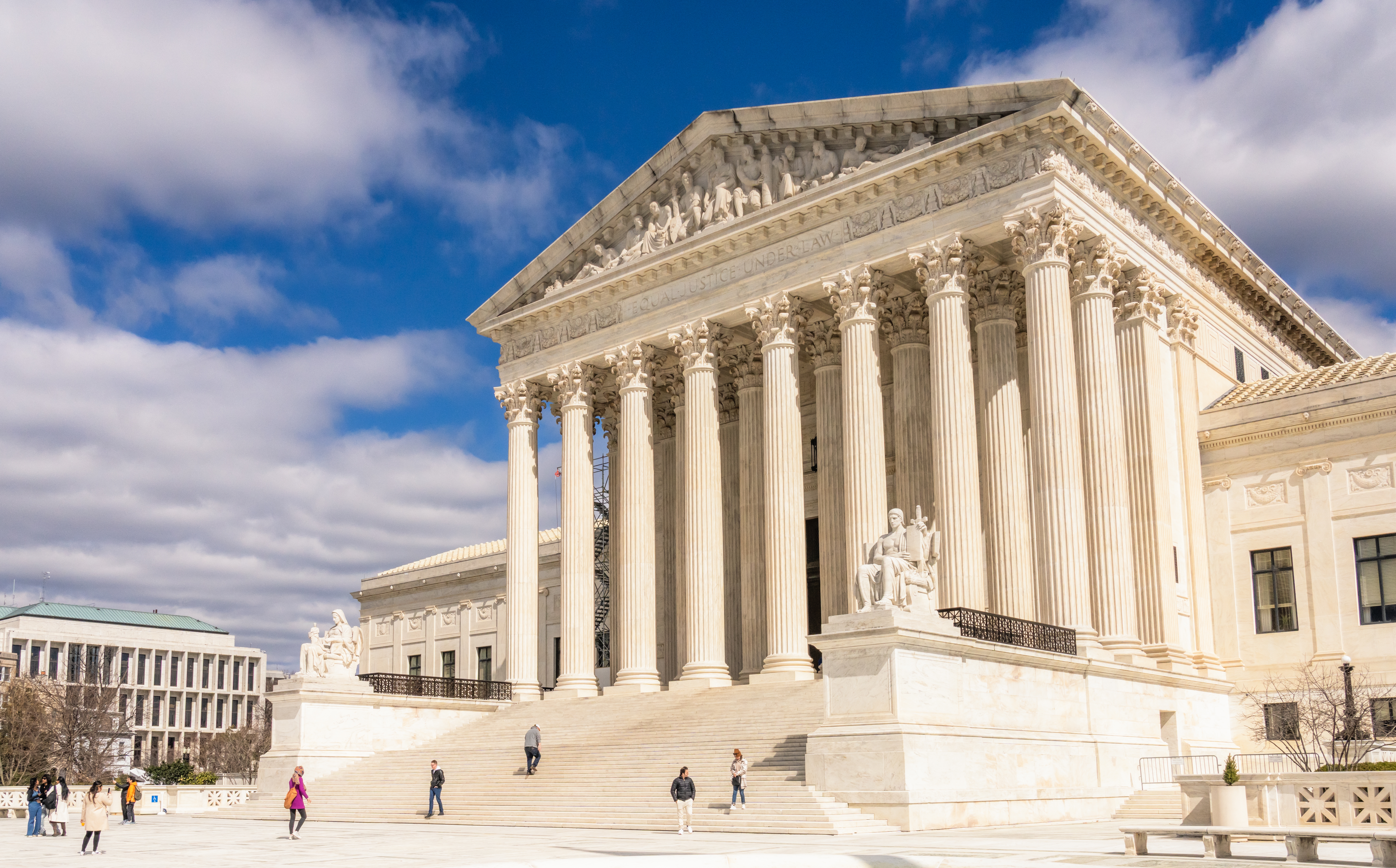 USAs høyesterettsbygning med folk som går på trappene, mot en delvis overskyet himmel