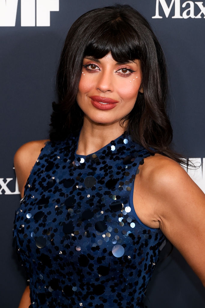 A idiosyncratic   poses connected  a reddish  carpet wearing a sleeveless sequin formal  with circular  embellishments