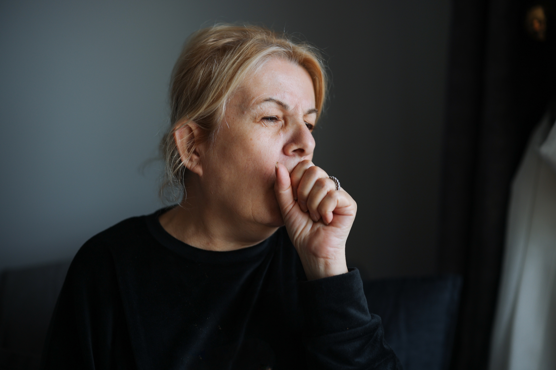 Person with thoughtful look  looking retired  a window, wearing a casual acheronian  sweatshirt, manus  raised thoughtfully to face