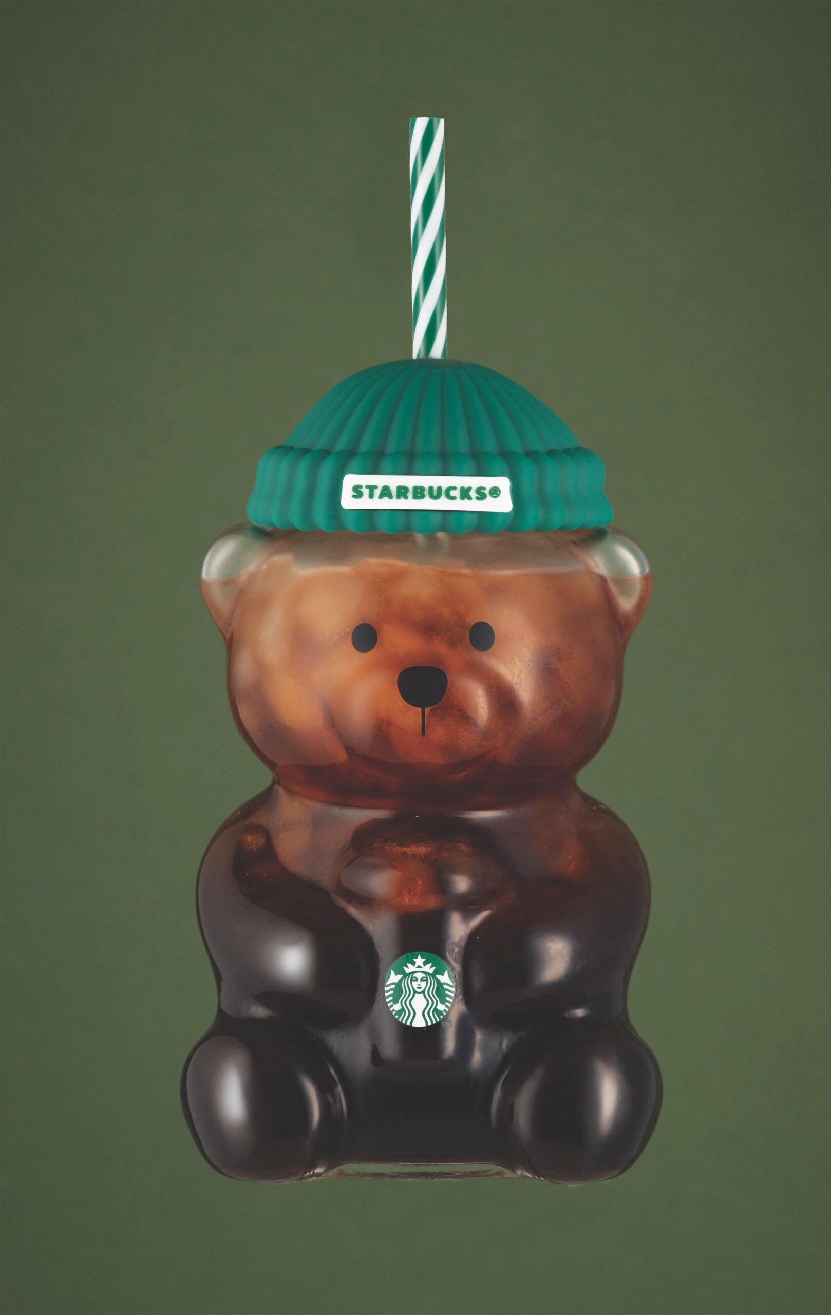 Starbucks teddy bear-shaped cupful  with a green-striped straw and beanie, filled with iced coffee