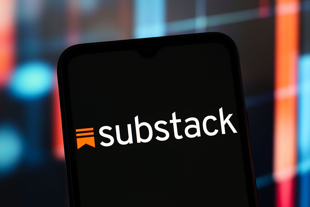 Smartphone displaying the Substack logo, acceptable   against a blurred integer  background