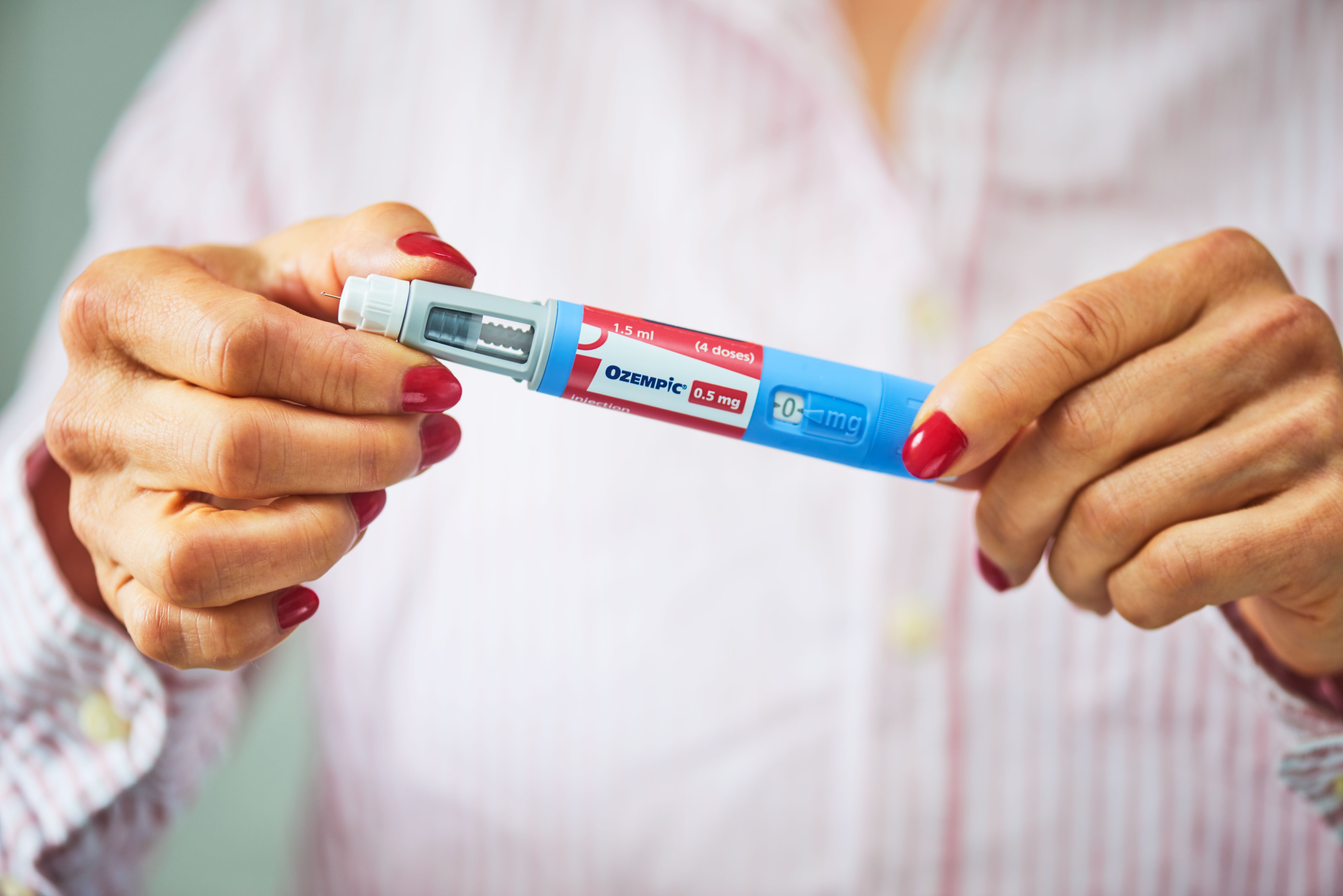 Person holding an Ozempic pen injector, utilized  for managing benignant   2 diabetes, against a blurred background