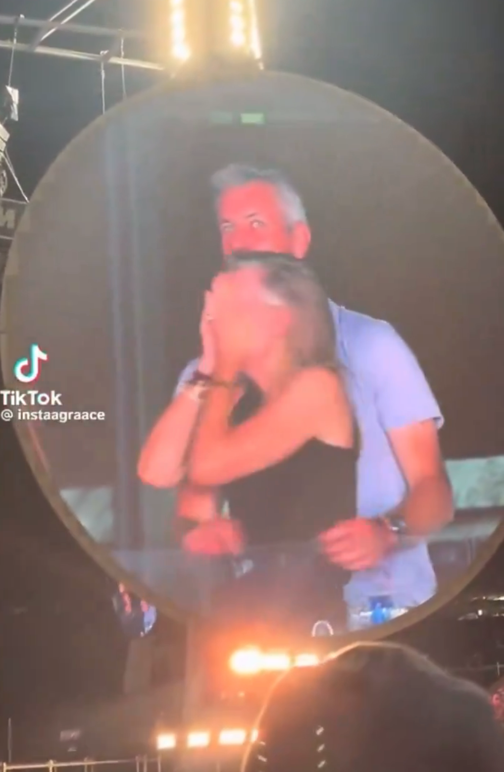 Two people on a concert screen, one surprised and covering their face, while the other stands behind, smiling. TikTok text overlay is visible