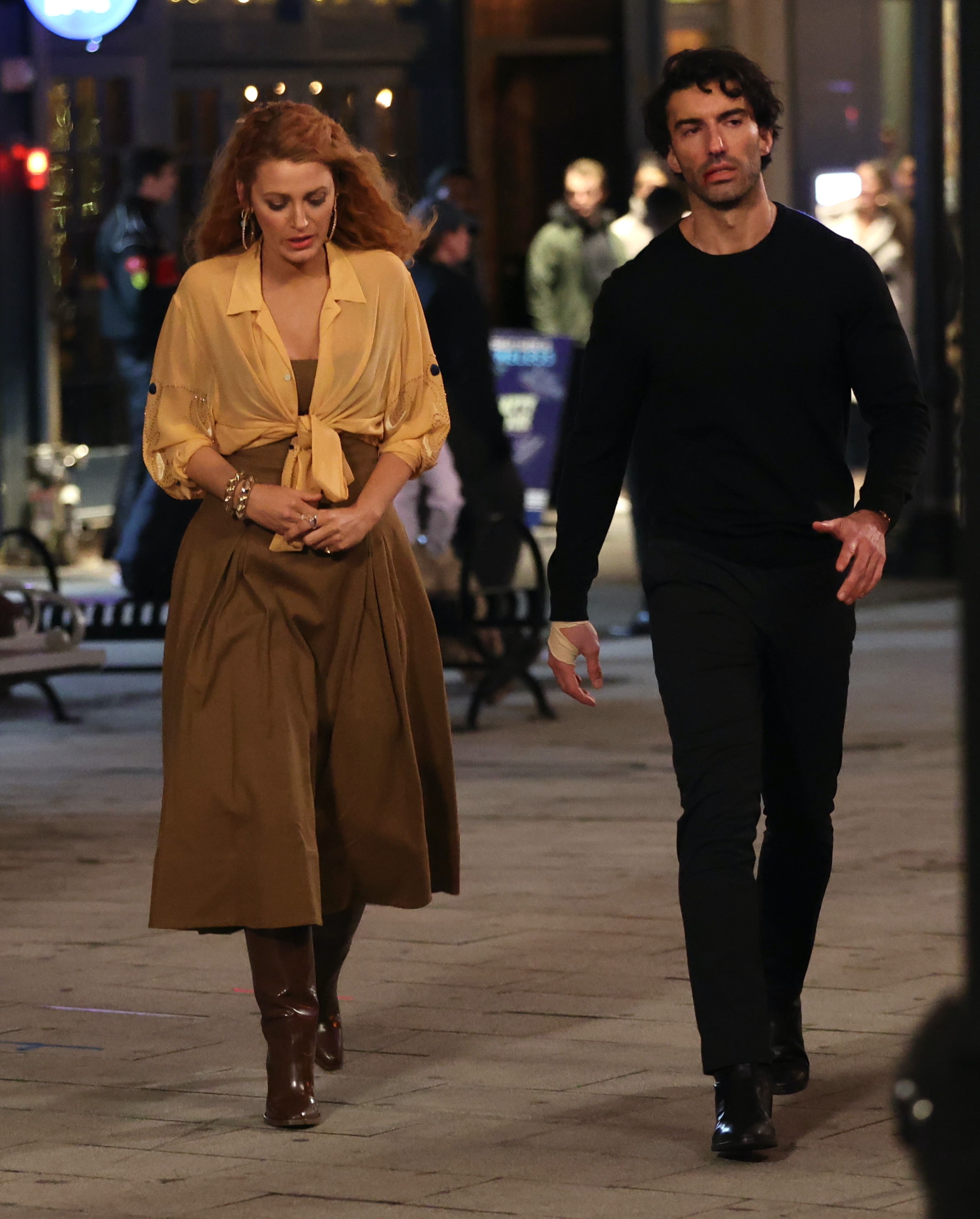 Two radical   walking connected  a metropolis  thoroughfare  astatine  night. One idiosyncratic   is wearing a casual blouse and skirt with boots, the different   is successful  a dark, casual outfit