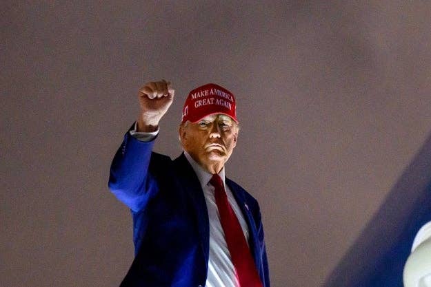 Person wearing a headdress  with a slogan, raising their fist successful  the air, captured successful  an outdoor mounting  astatine  night