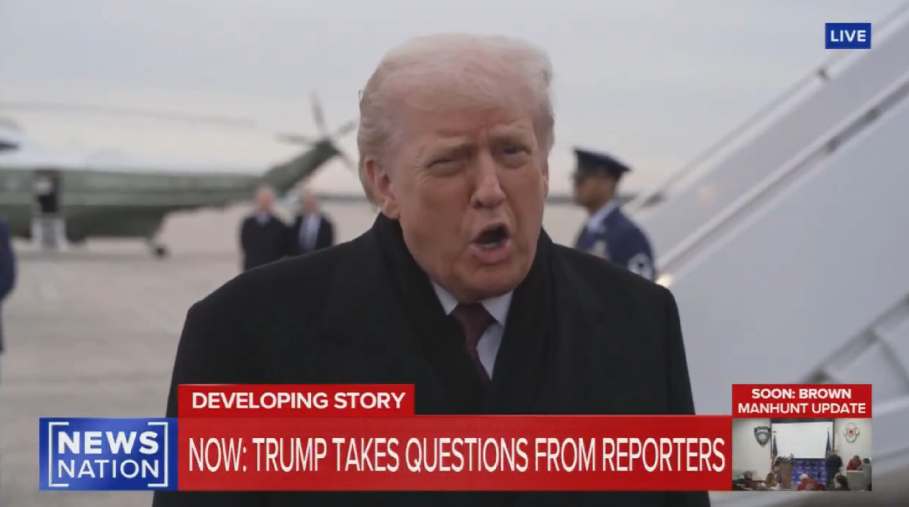 En person snakker med journalister i nærheten av et fly, med en nyhetsticker som sier 