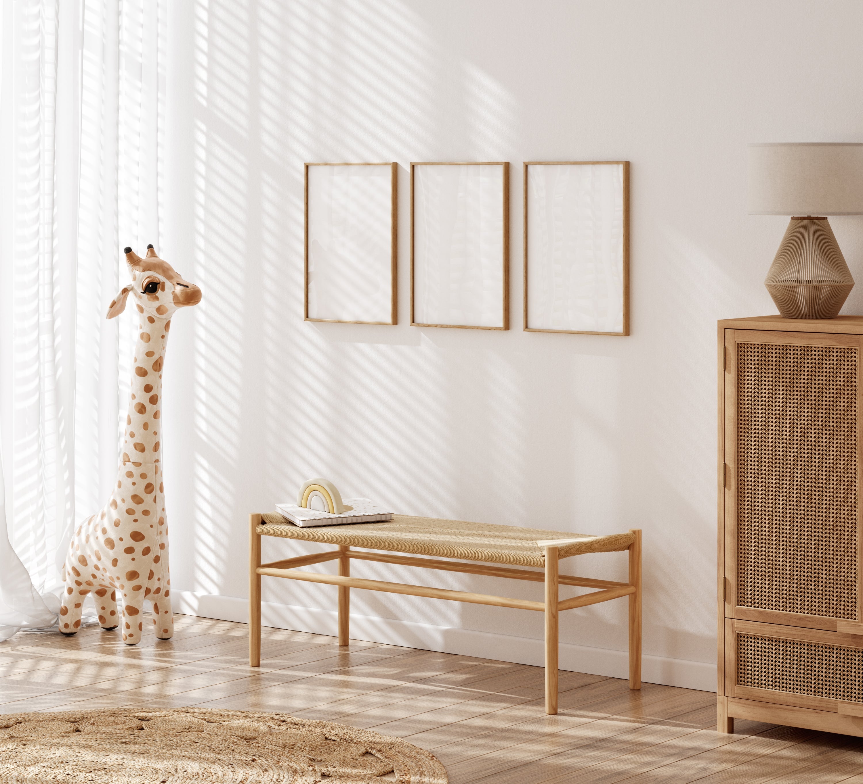 Minimalist nursery with giraffe toy, wicker cabinet, and wooden bench. Three blank frames on the wall add to the serene, neutral decor