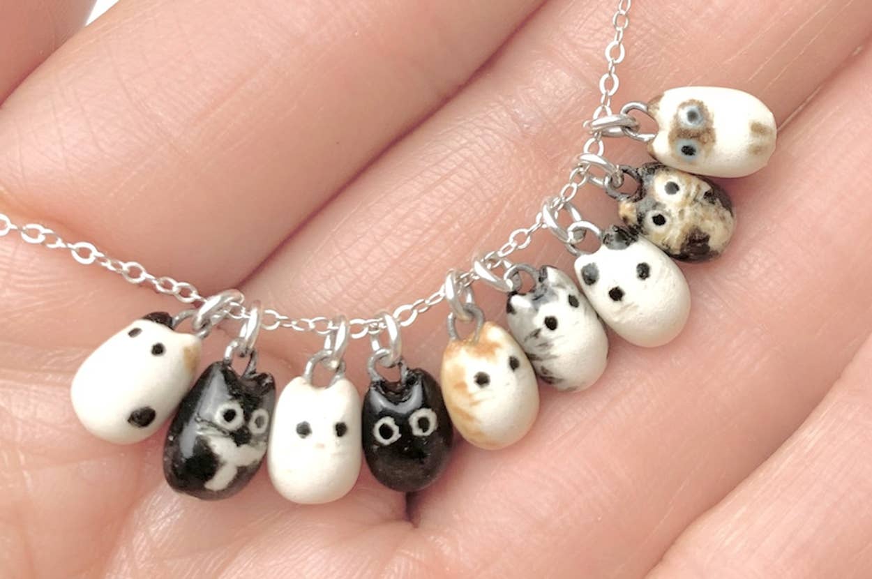 Hand holding a necklace with charms shaped like small owl faces