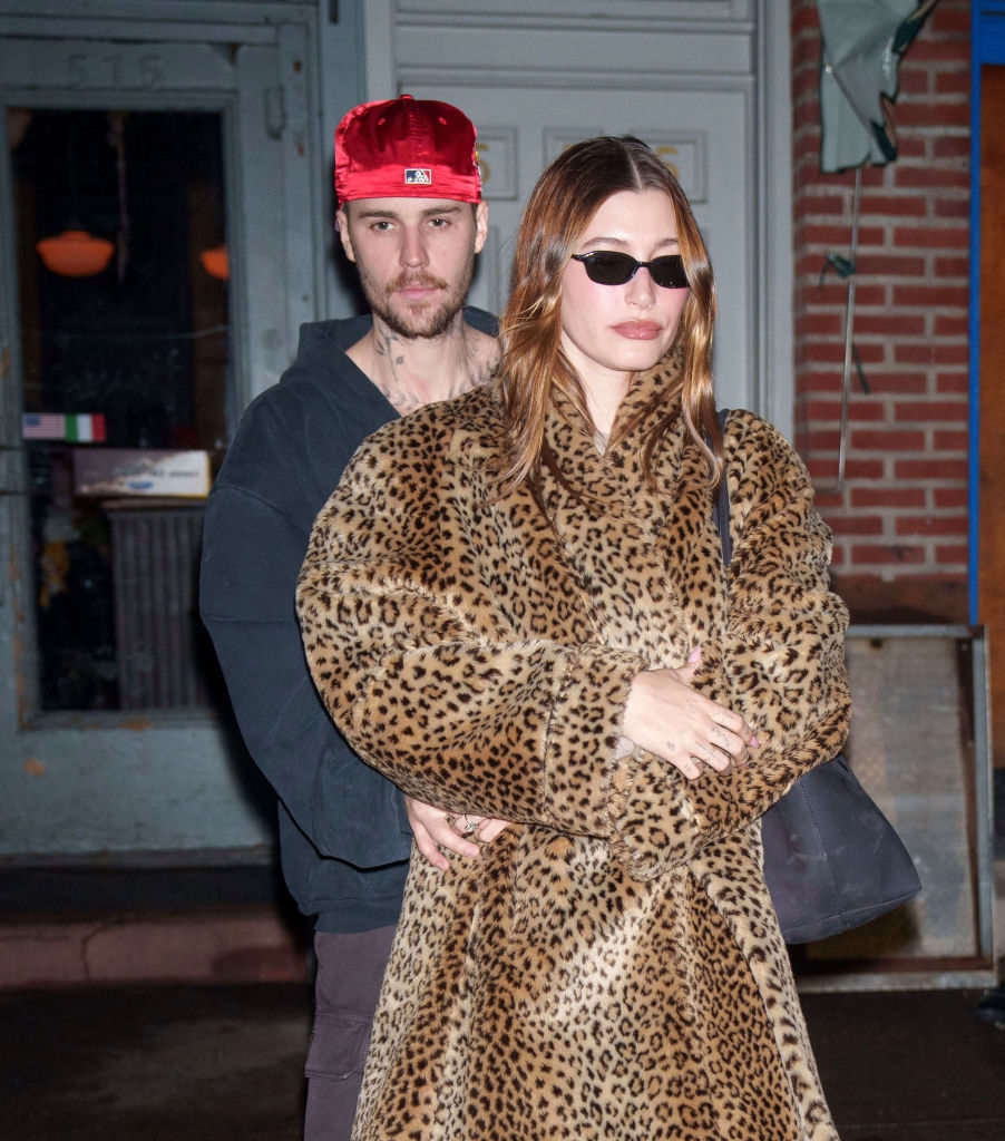 Two individuals outside, 1  wearing a headdress  and casual attire, the different   successful  a leopard-print overgarment  and sunglasses