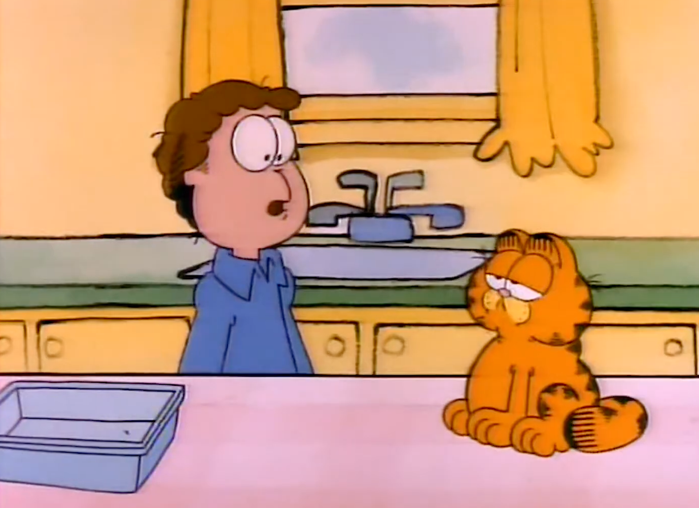 Cartoon image of a man in a blue shirt talking to a grumpy-looking orange cat sitting on a kitchen counter