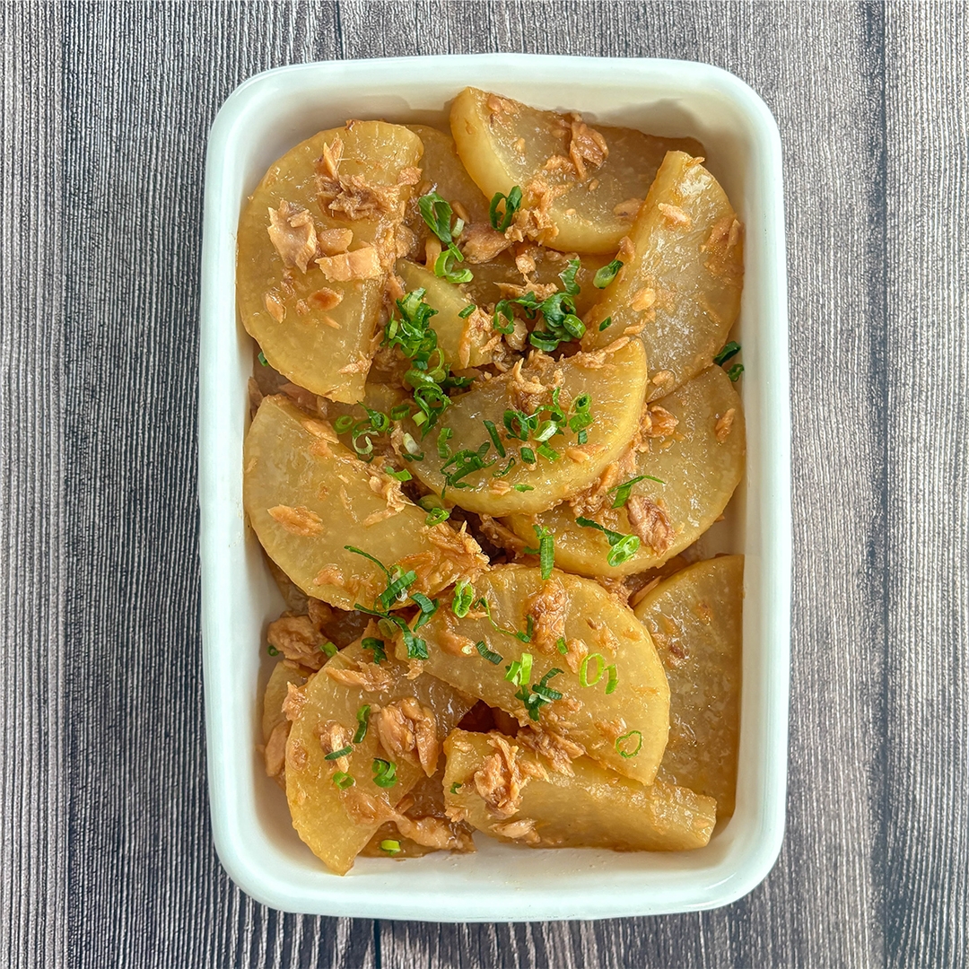 大根とマグロ油漬けの甘辛煮が白い器に盛られている。小ネギが散らしてある。