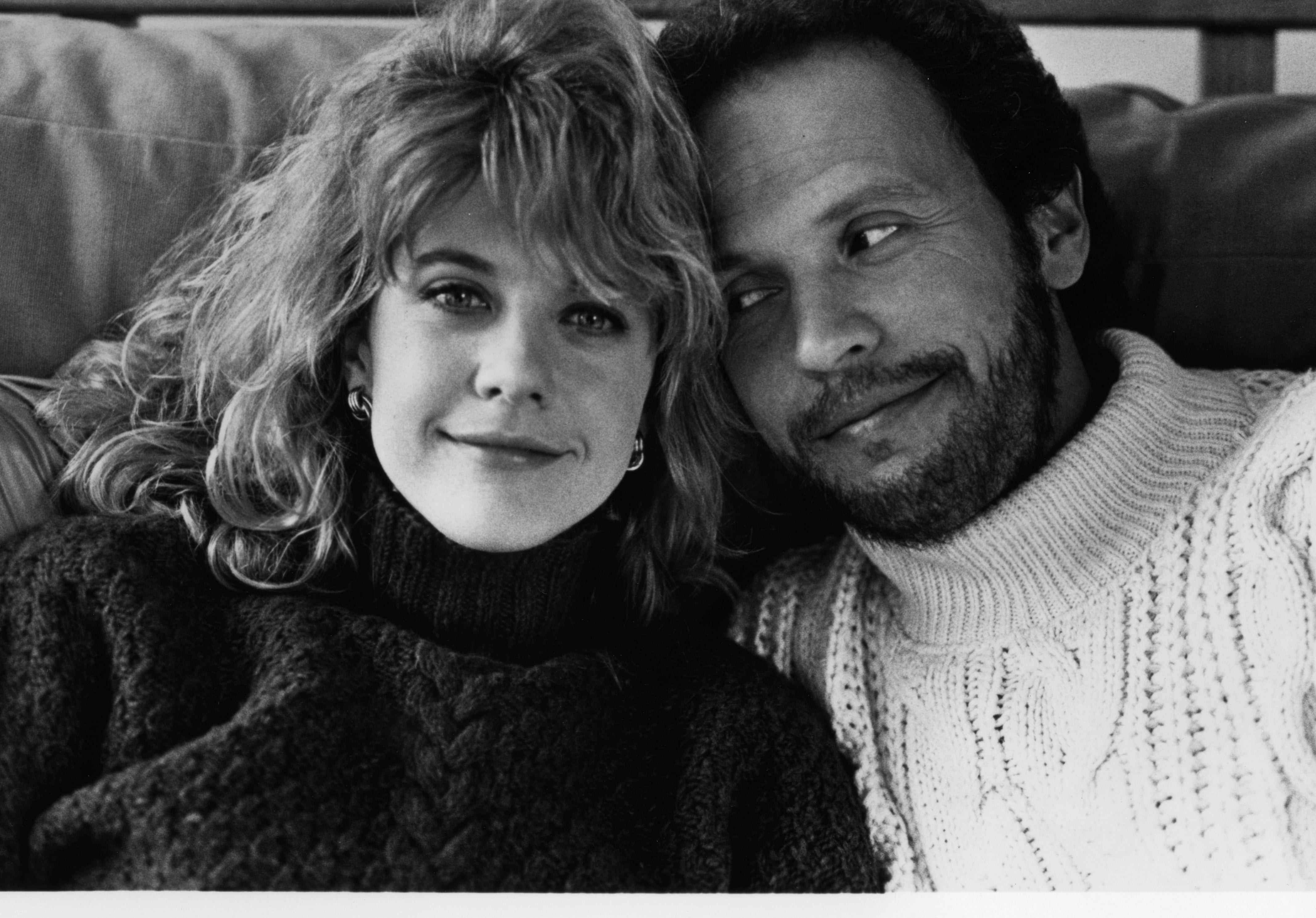 Two radical   seated closely, smiling warmly. The idiosyncratic   connected  the near  wears a turtleneck, and the idiosyncratic   connected  the close    wears a knit sweater