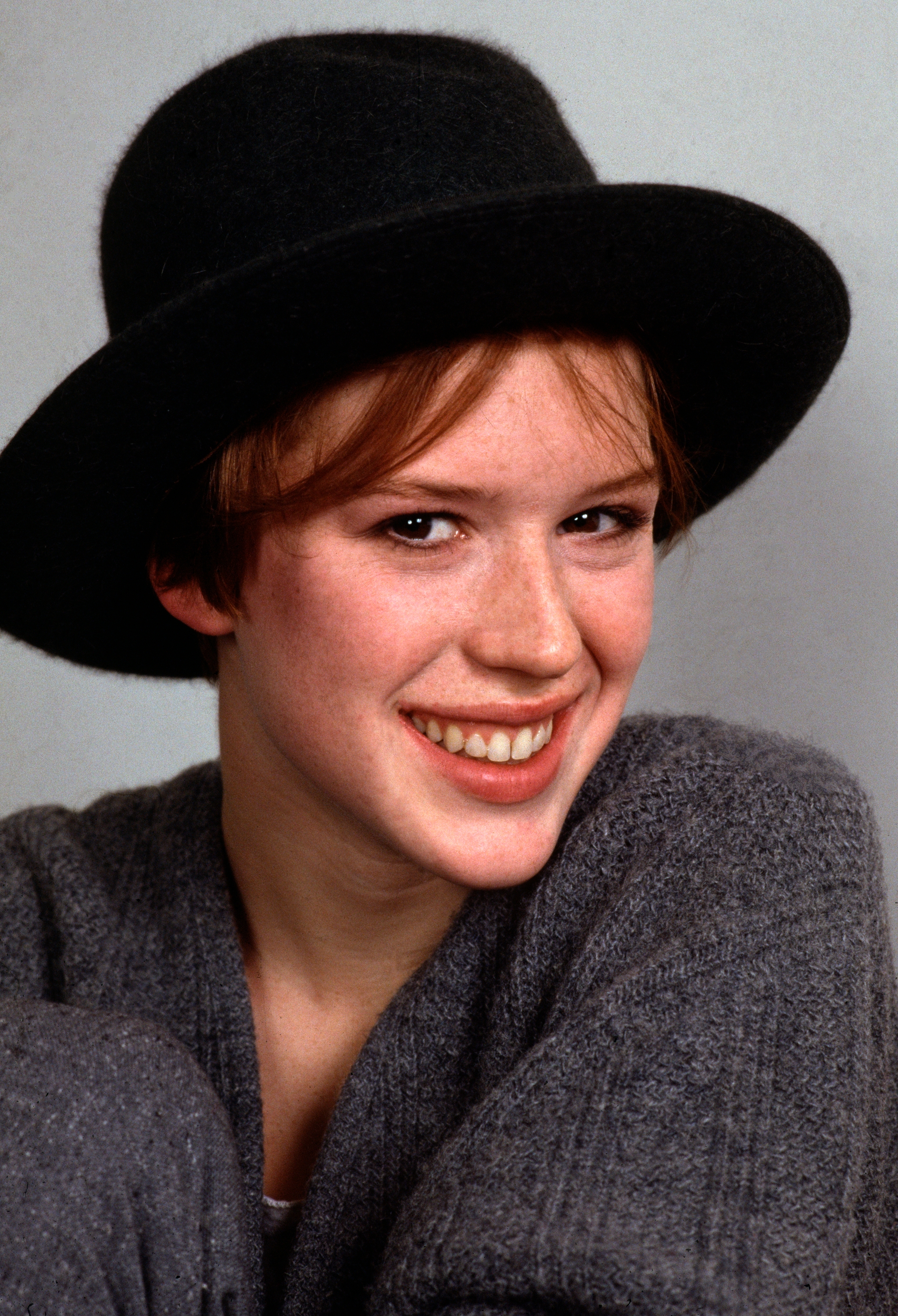 Person wearing a acheronian  chapeau  and textured sweater, smiling warmly astatine  the camera