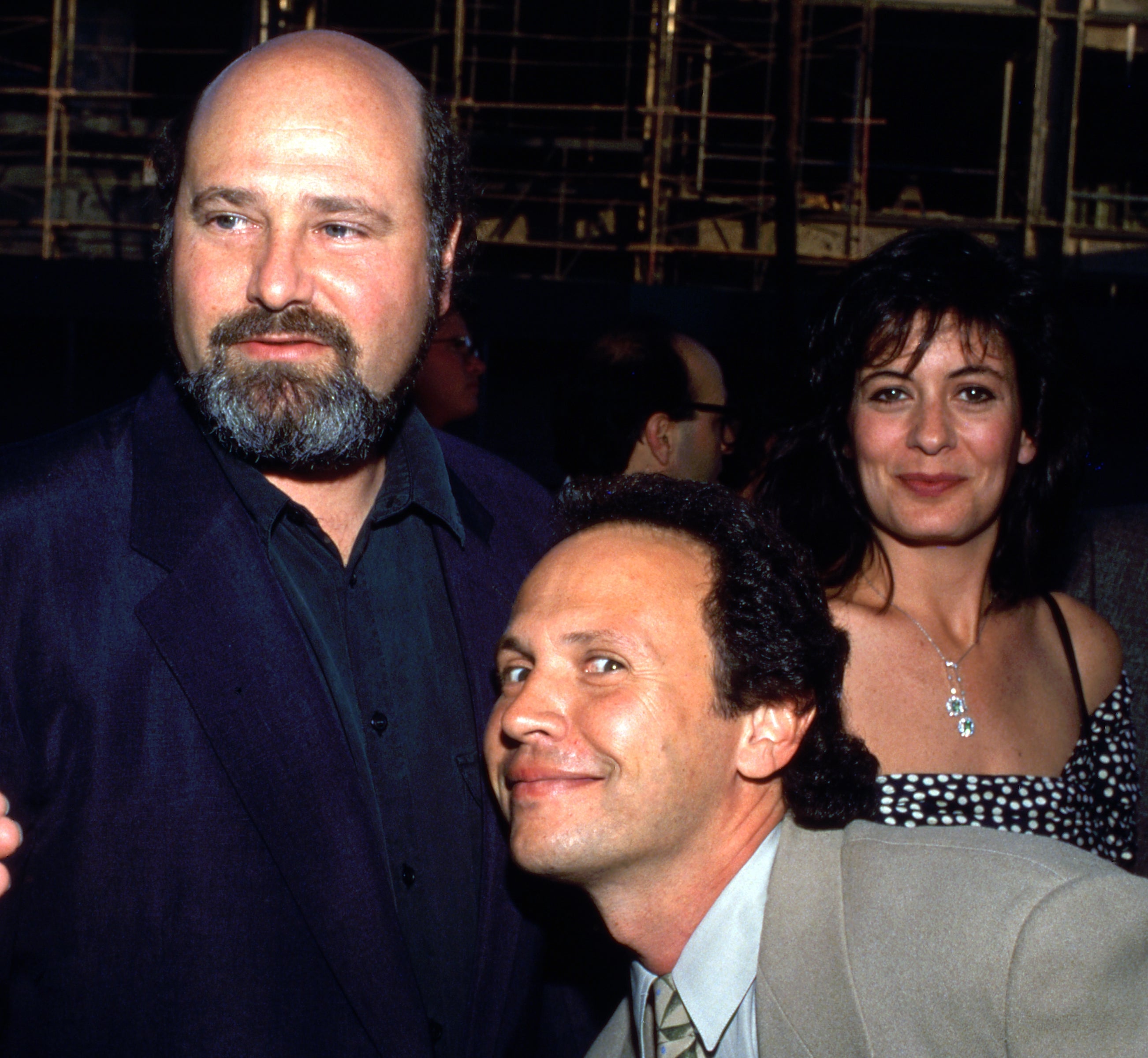 Group of radical   posing astatine  an event; 1  idiosyncratic   is wearing a suit   jacket, different  a patterned dress, and a 3rd  smiling successful  a suit