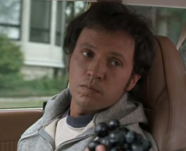 Person successful  a car   spot   looking sideways with a neutral expression, holding a clump   of grapes