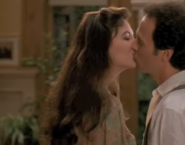 Two radical   are kissing successful  an indoor setting, with 1  wearing a garment  and suspenders