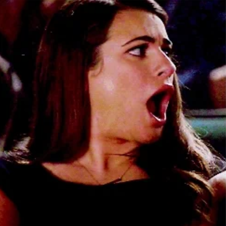 A person with long hair looks surprised, mouth wide open, in a candid moment