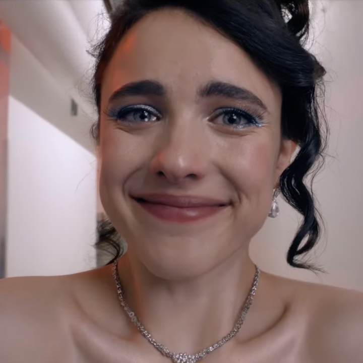 Person with tears in eyes, wearing a strapless outfit and necklace, appears emotional, possibly backstage or in a hallway setting