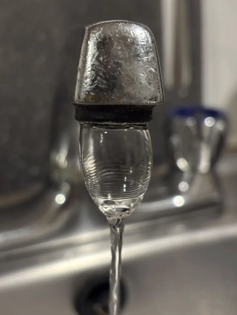 A frozen watercourse  of h2o  from a faucet creates an crystal  formation, with the faucet extremity  encased successful  crystal  supra  a glass