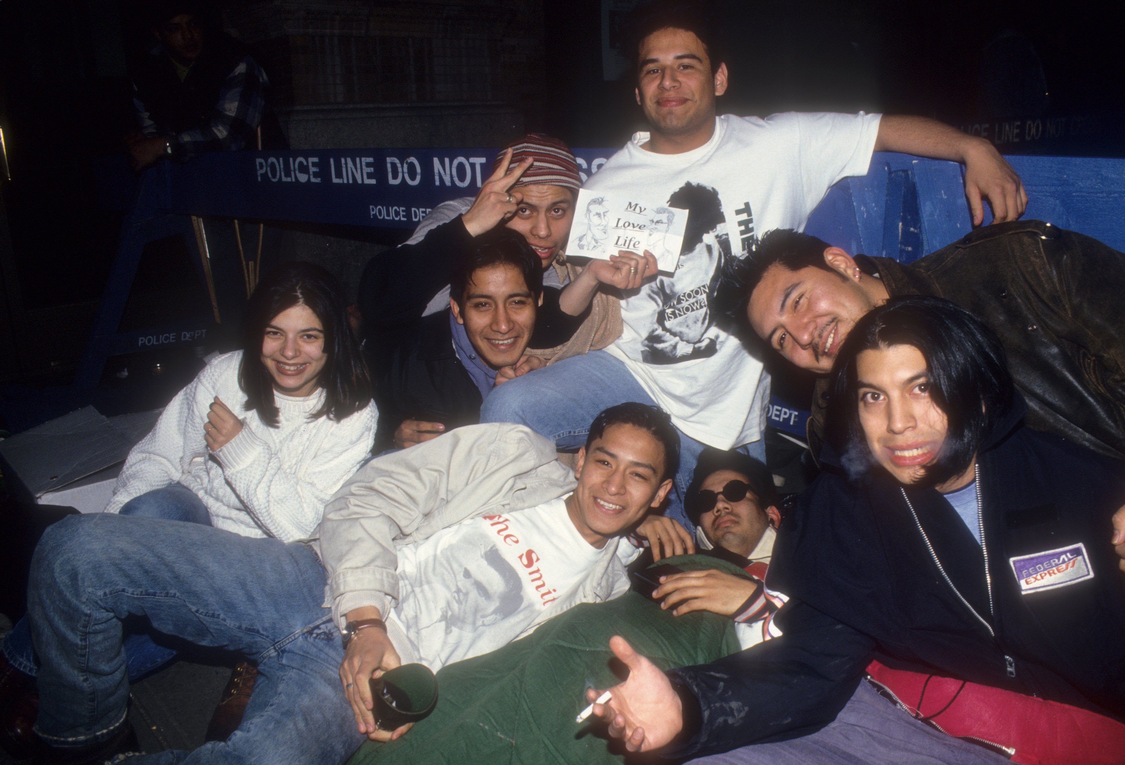 Group of young radical sitting unneurotic casually astatine night, smiling for a photo, with 1 holding a sign