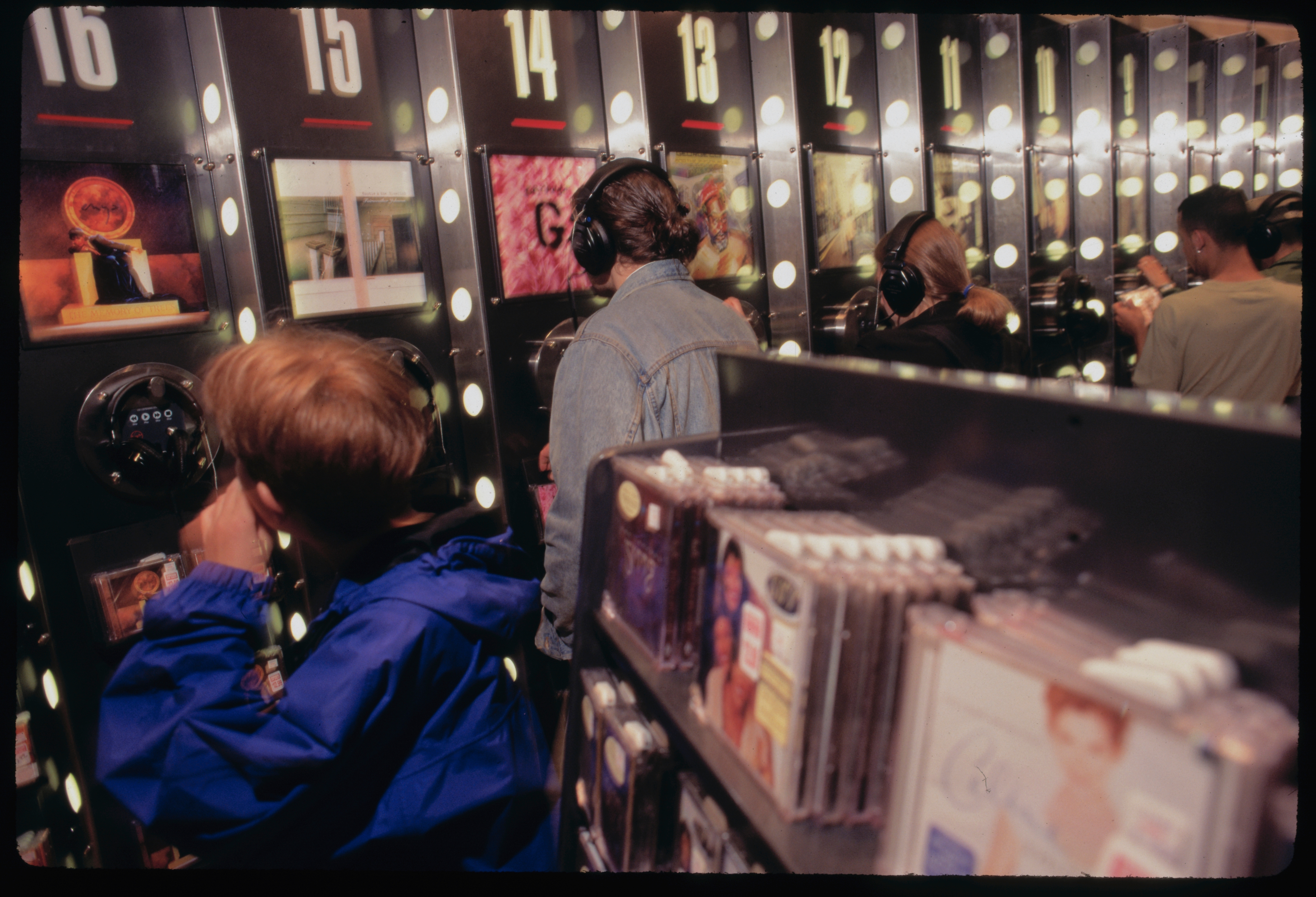 People utilizing headphones astatine euphony listening stations with CDs displayed, reminiscent of 1990s euphony stores