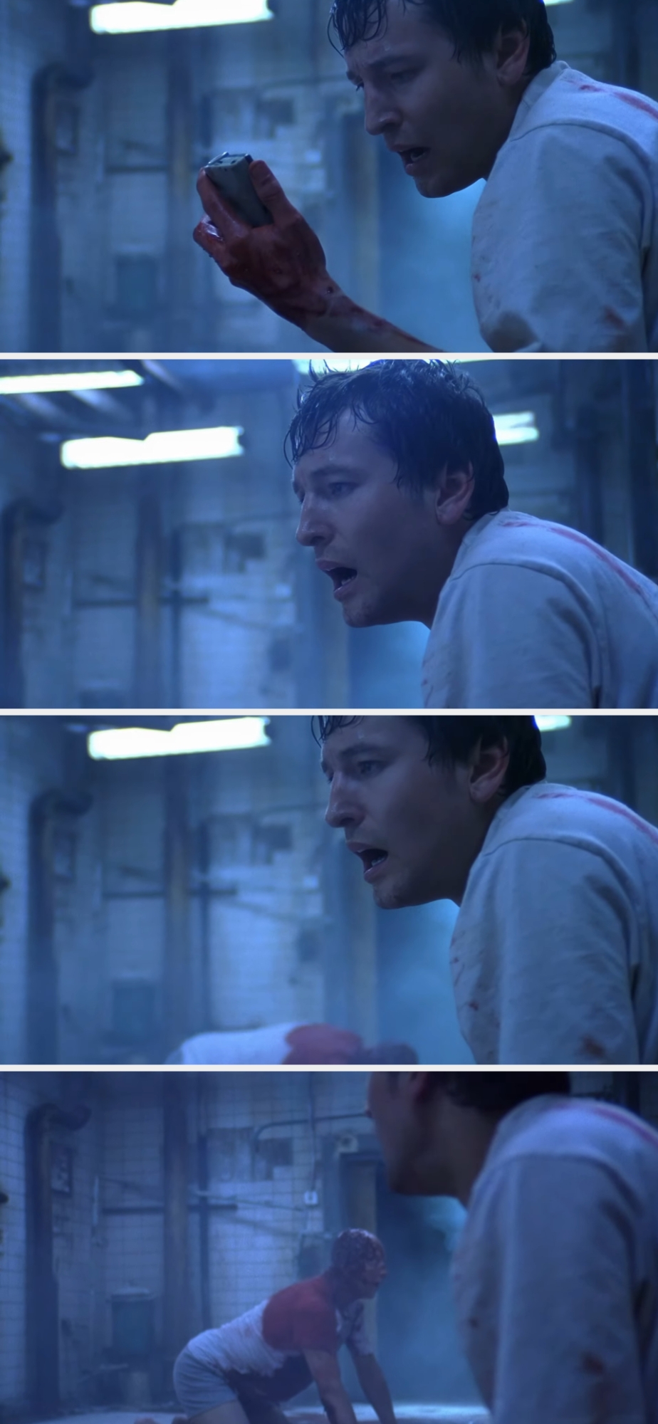 A man in a dim, industrial setting appears tense while holding a saw. He kneels with resolve, seemingly preparing for a drastic action