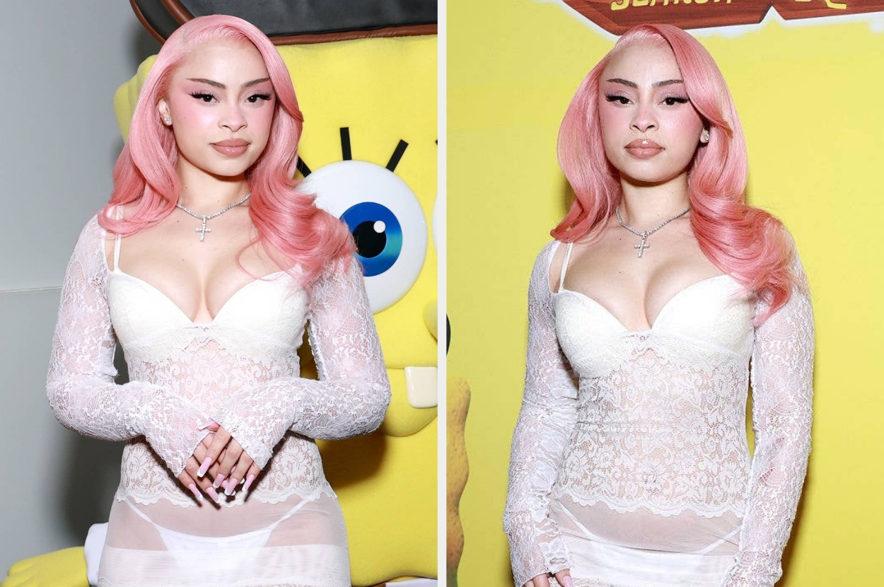 Person in lace outfit with long, wavy pink hair poses in front of SpongeBob-themed backdrop, showcasing stylish and elegant appearance
