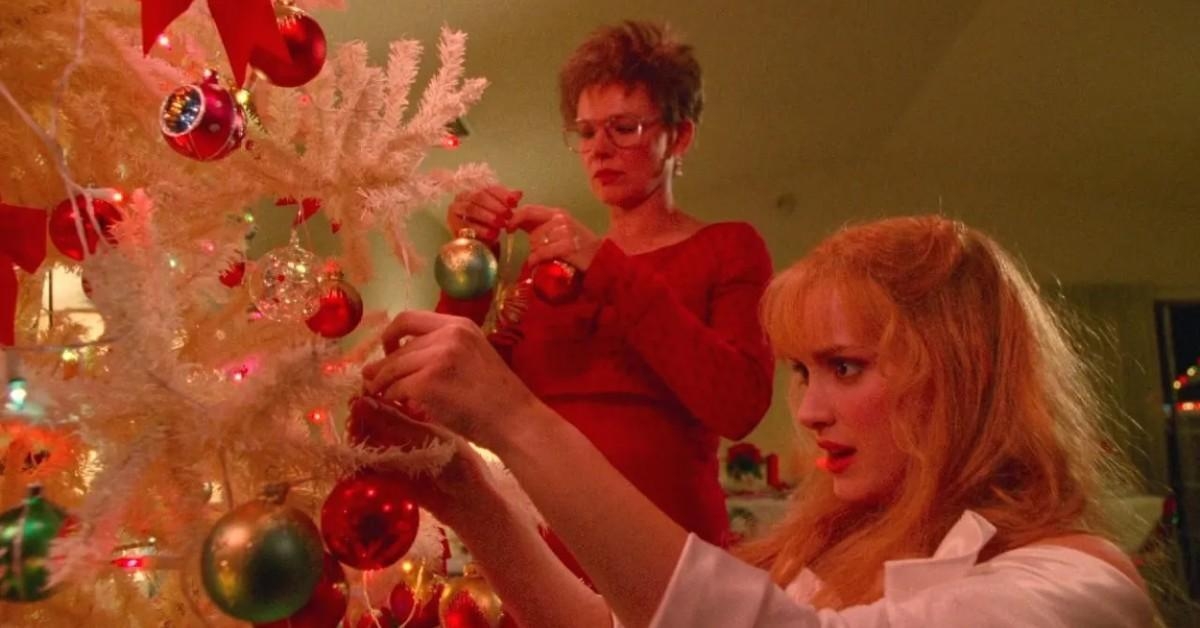 Two women decorate a achromatic  Christmas histrion   with ornaments indoors
