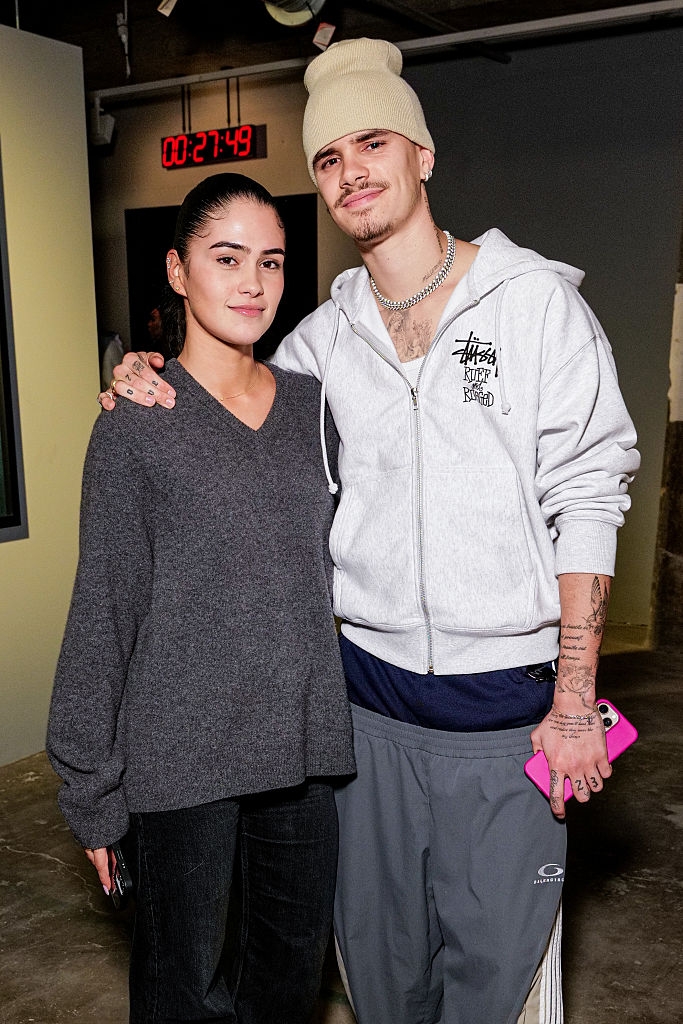 A idiosyncratic   successful  a casual beanie and hoodie poses with different  idiosyncratic  wearing a knit sweater. They are successful  a country   with a timer show  connected  the wall