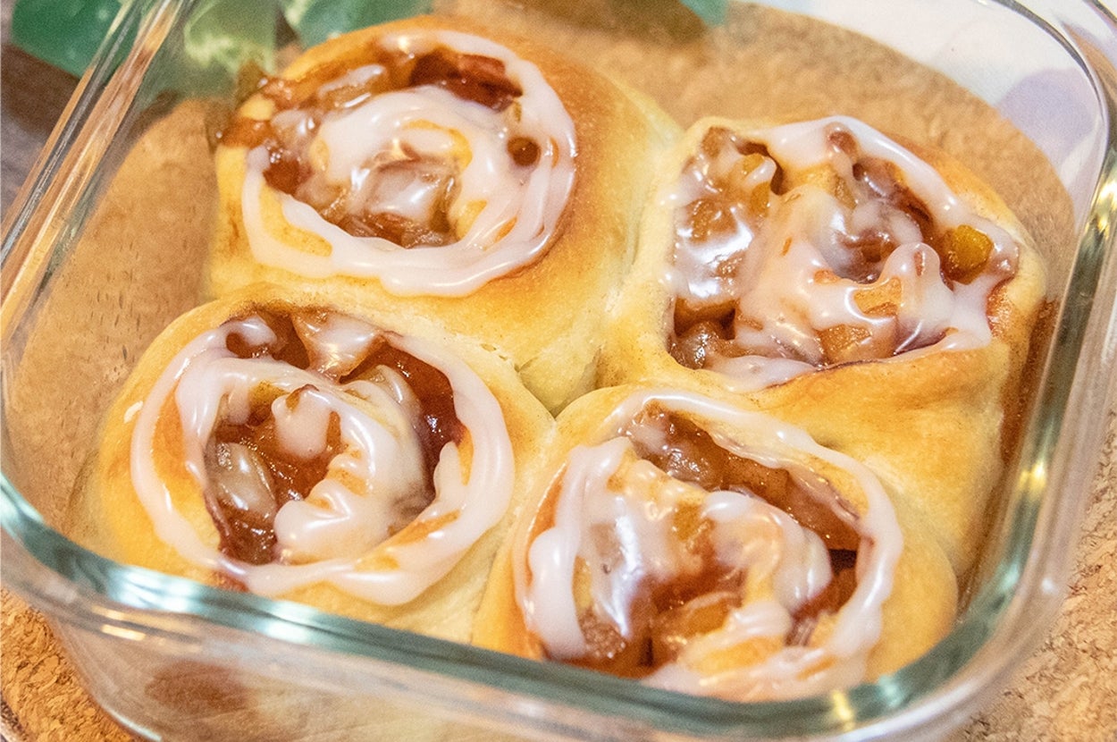 ガラス容器に入った4つのアイシングがかかったりんごのシナモンロール。