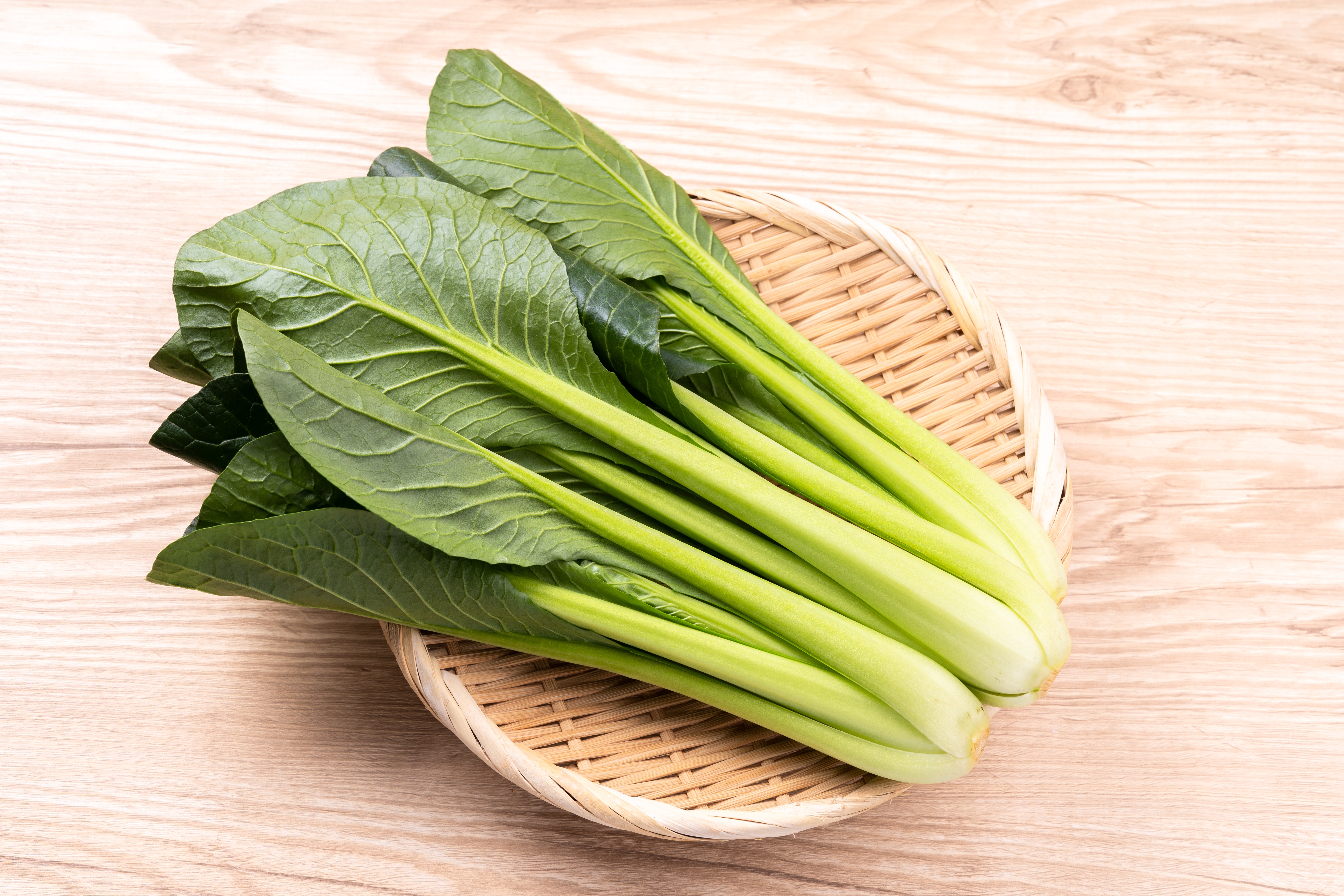 ざるに盛られた新鮮な葉物野菜の束。