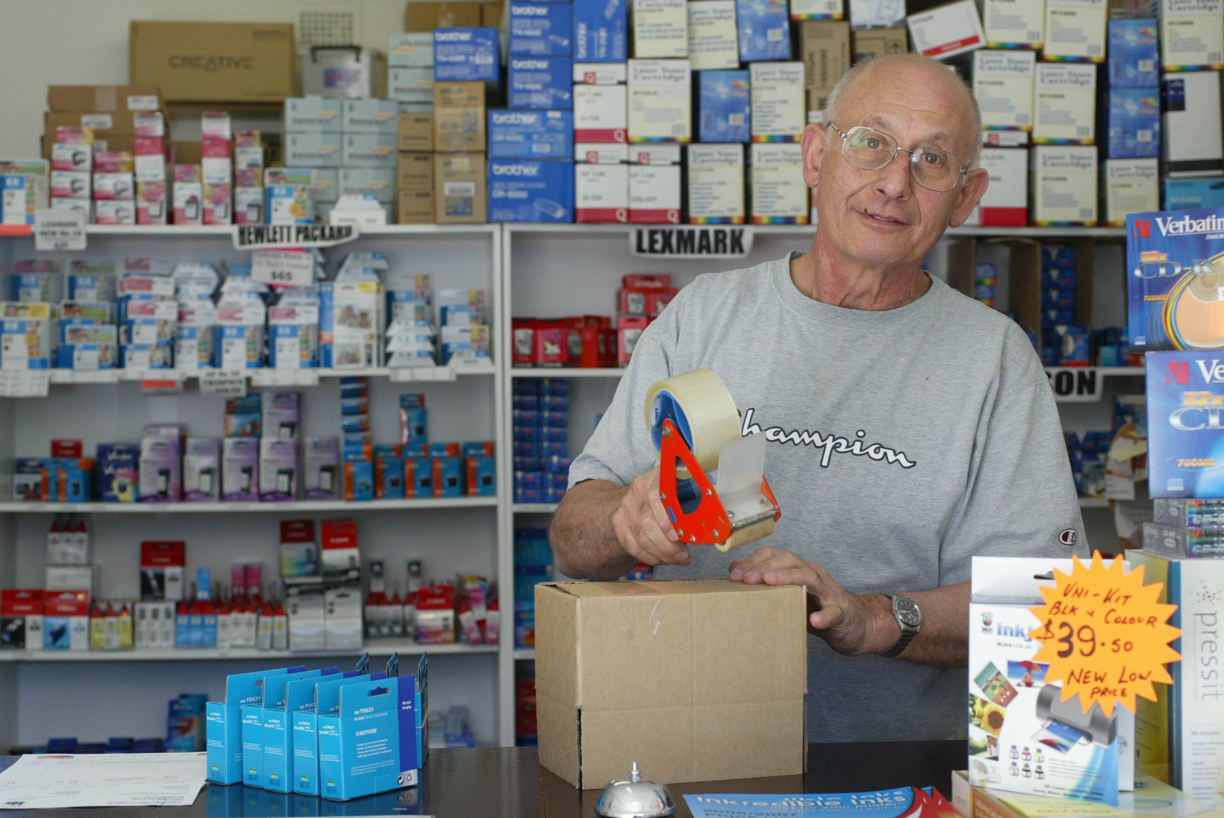 A antheral   lasting  down  a antagonistic  successful  a store, packing a container  with tape. Shelves filled with assorted  bureau   supplies are disposable   successful  the background