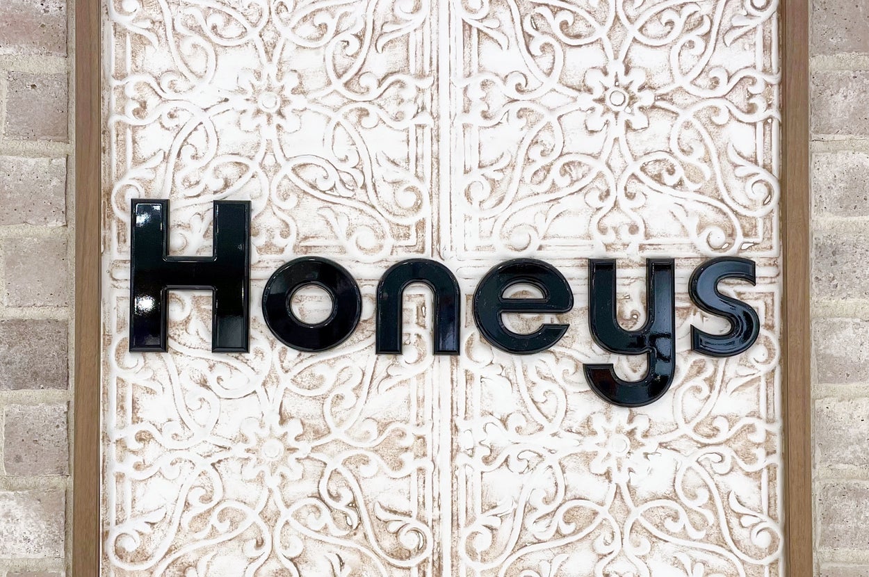 「HONEYS」と書かれた装飾された壁のサイン。
