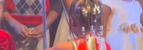 ステージ上で赤いストライプのドレスを着た子どもが歌っている様子。