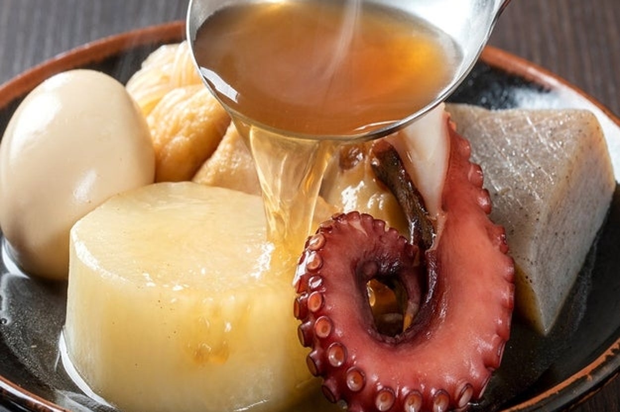 おでんの具材に出汁をかけている様子。大根、卵、たこ、こんにゃくなどが器に盛り付けられている。