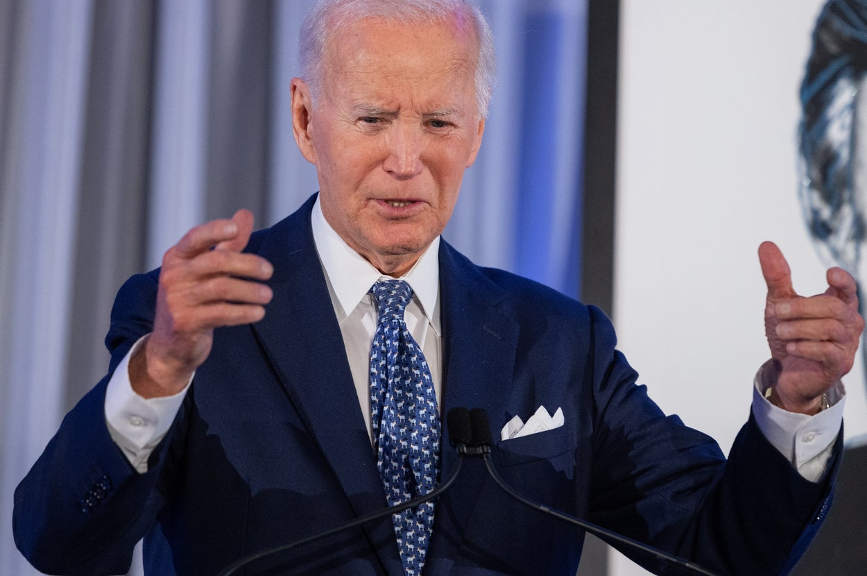 男性がスピーチ中に身振りを交えながら話している様子。フォーマルなスーツを着用。