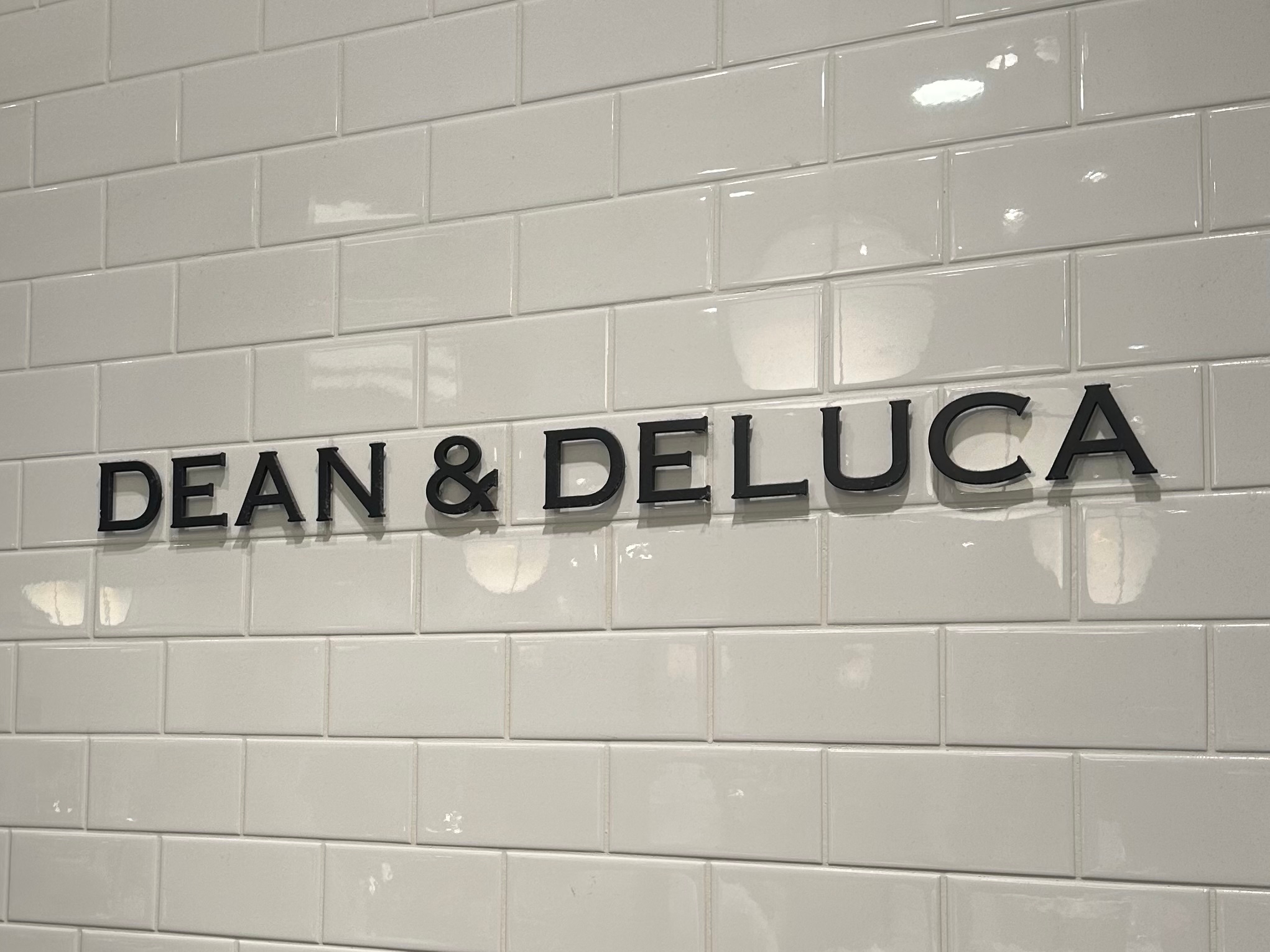 壁のタイルに「DEAN & DELUCA」の文字が表示されています。