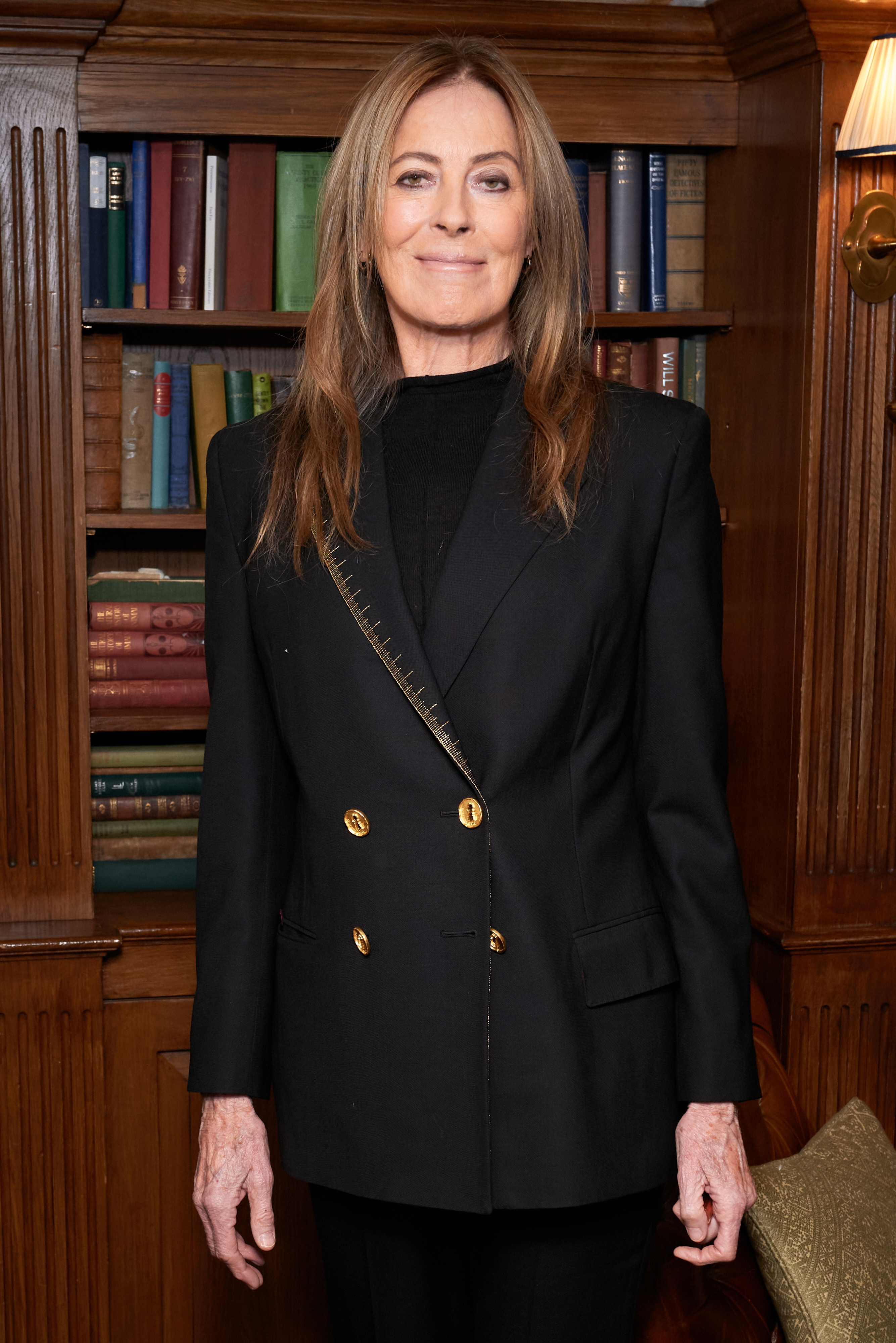 Kathryn Bigelow successful  a tailored achromatic  double-breasted blazer stands successful  a room  with bookshelves successful  the background