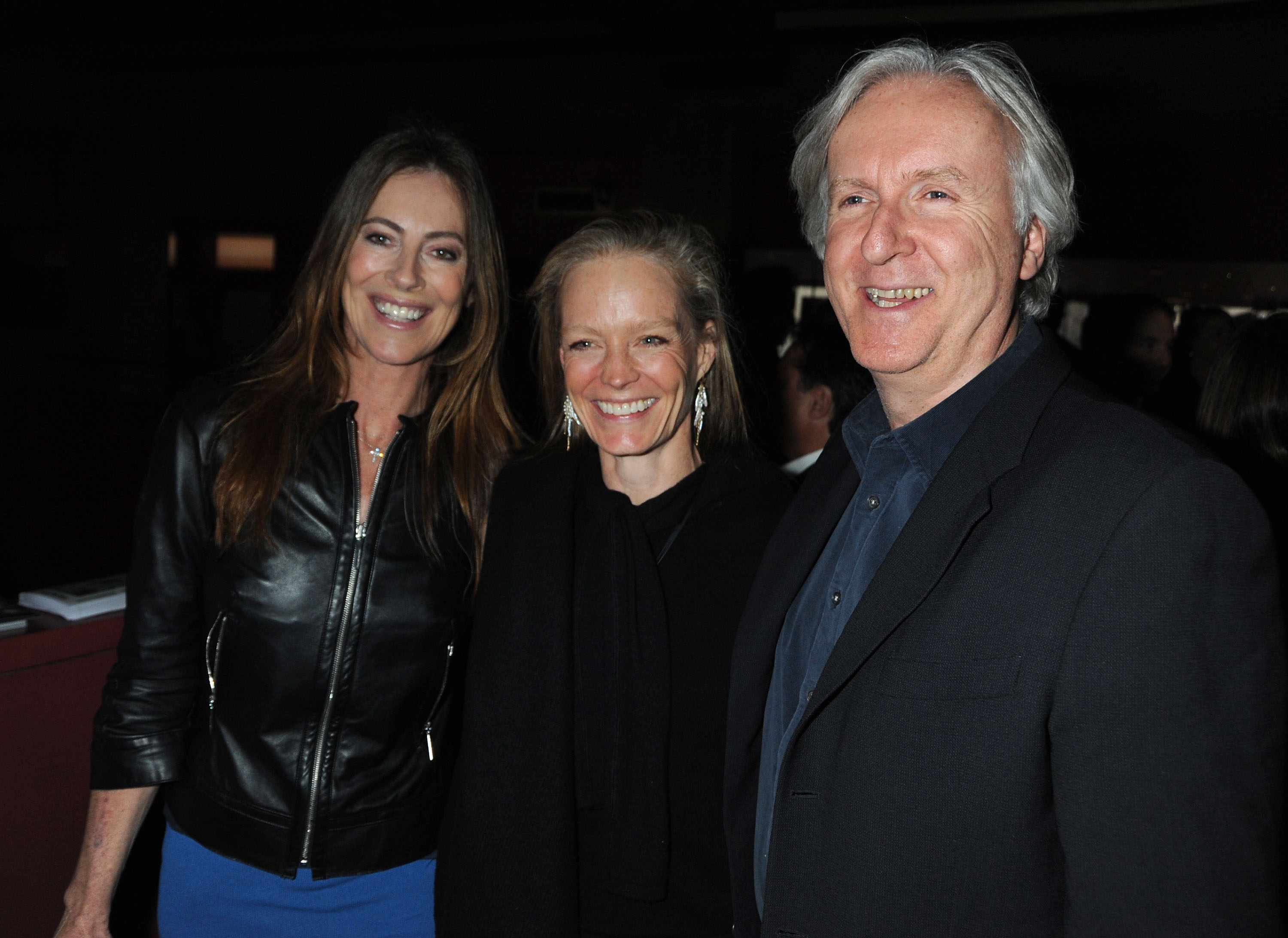 Three radical   are smiling astatine  an indoor event. The pistillate   connected  the near  is wearing a leather jacket