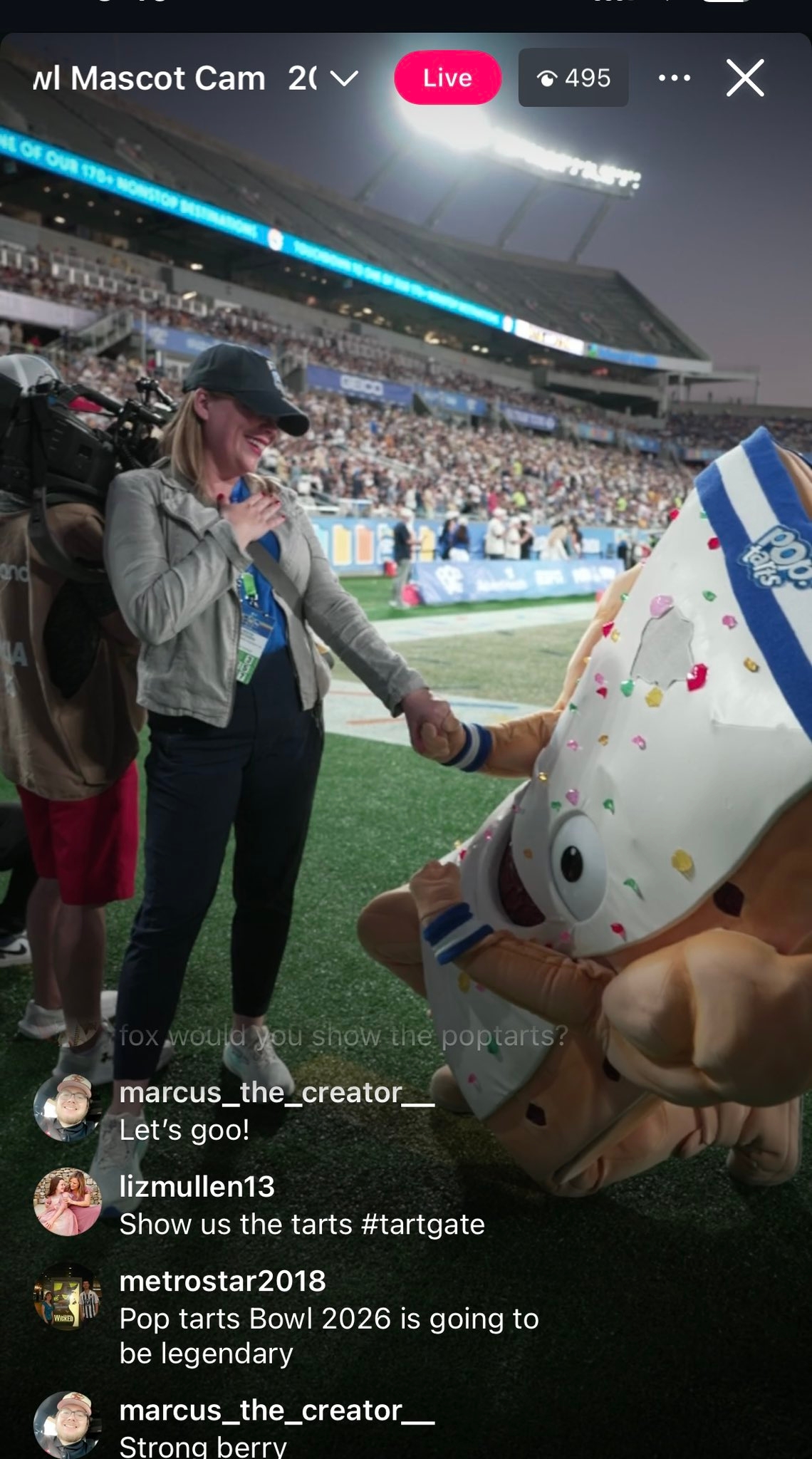 Person dressed arsenic  a Pop-Tart mascot kneeling connected  a shot   field, shaking hands with a smiling pistillate   with a headset. Crowd disposable   successful  the background