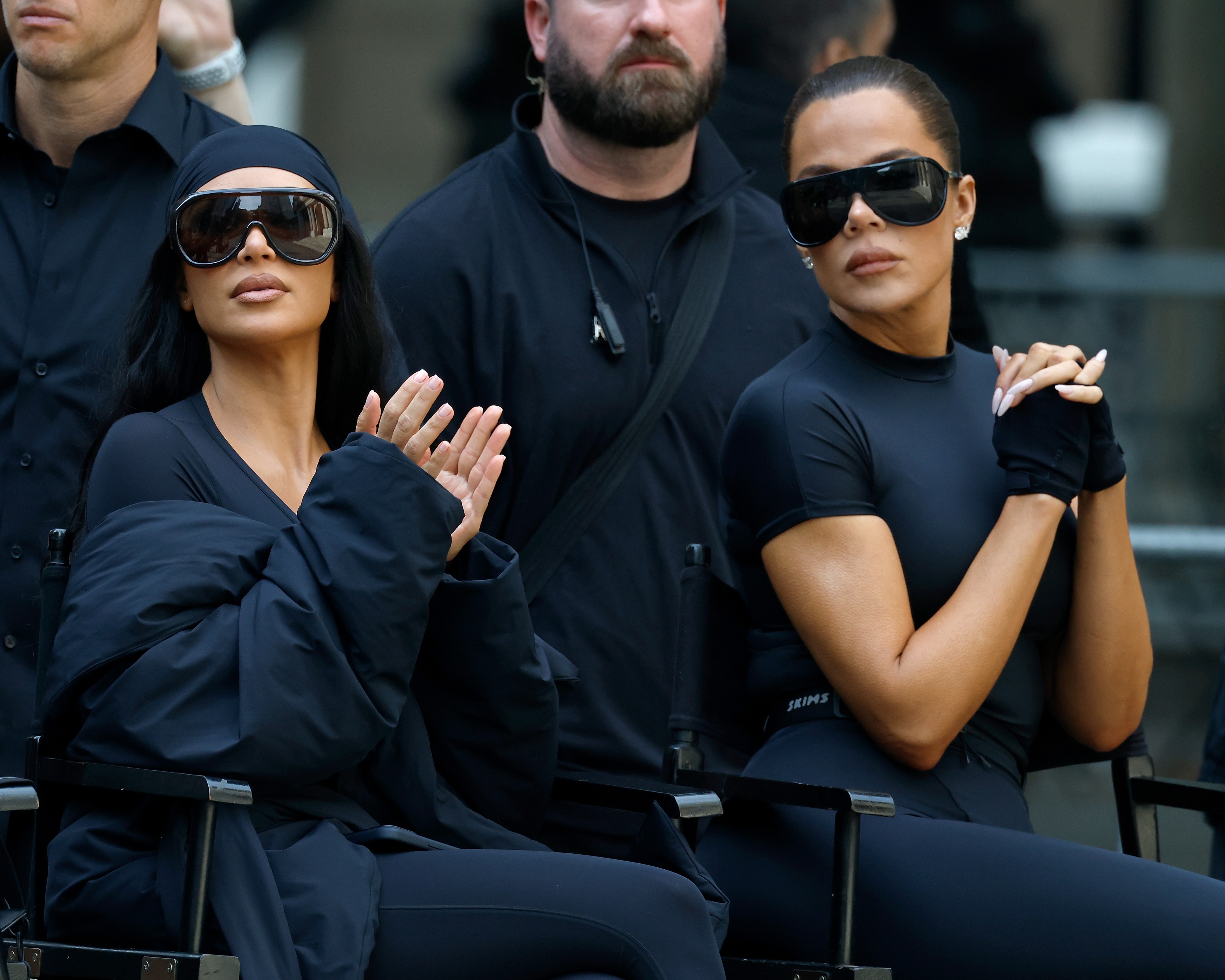 Kim and Khloe Kardashian successful  sleek attire and oversized sunglasses be  an outdoor event, sitting adjacent  to each   different   and appearing focused
