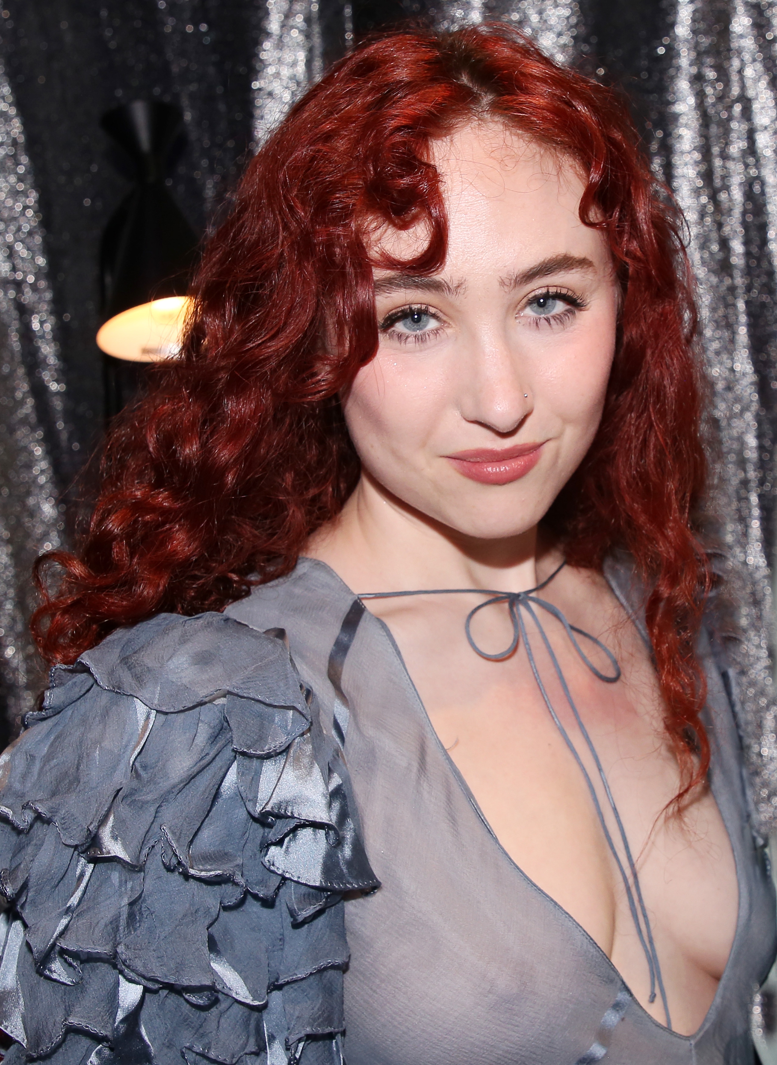 Person med krøllete hår i et rufsete, rent antrekk på et arrangement